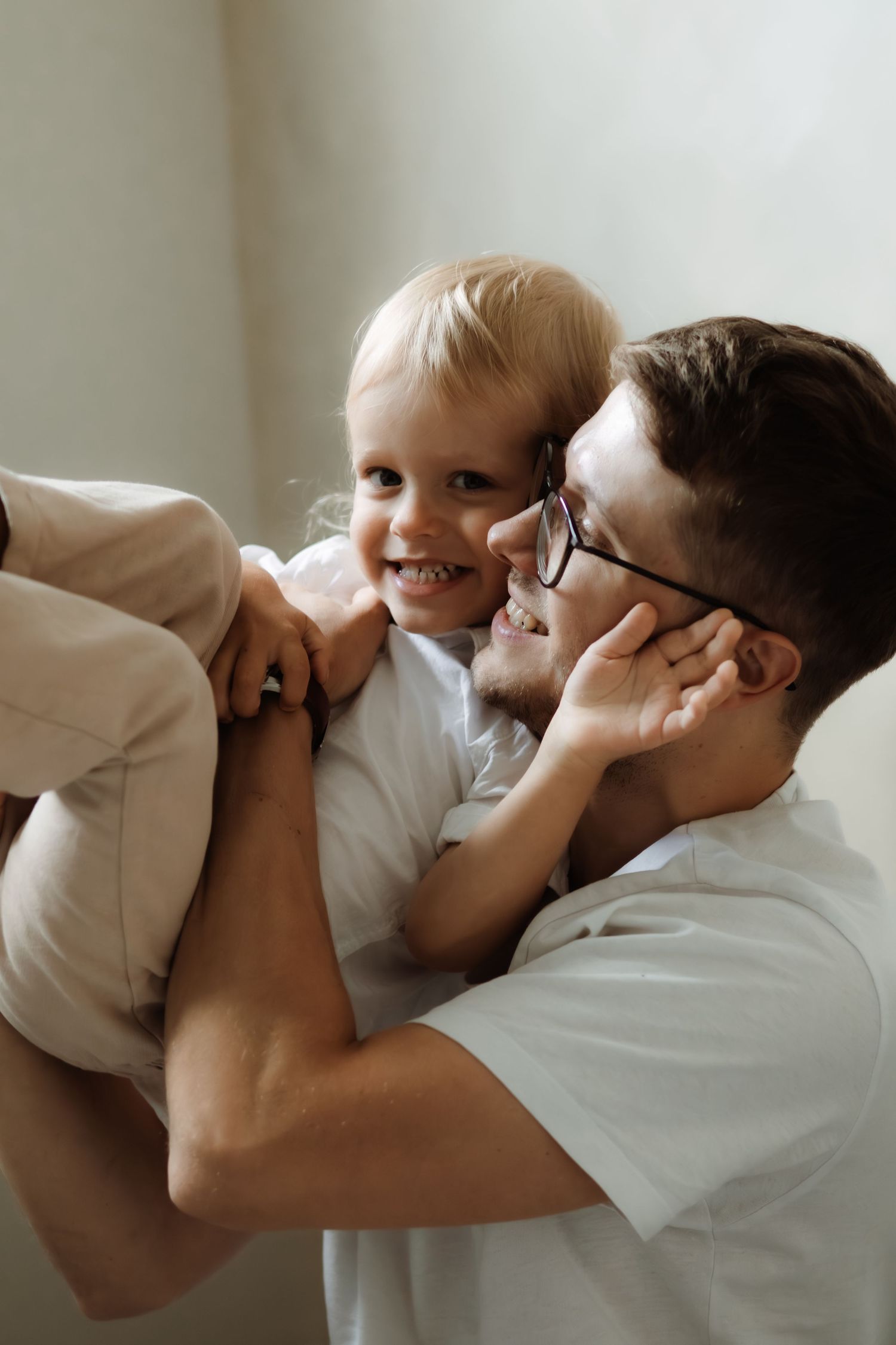 A tender moment captured in a series of photos showing a parent and child snuggling together on a white bed.