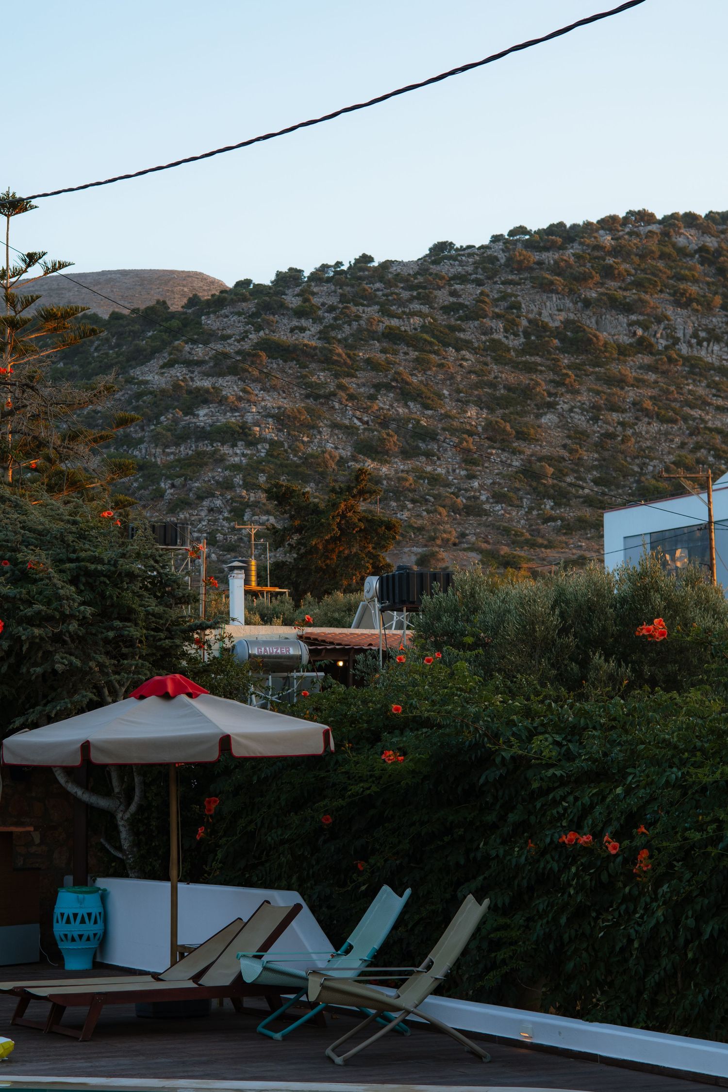 Outdoor lounge chairs on a patio with hills and mountains in the background.
