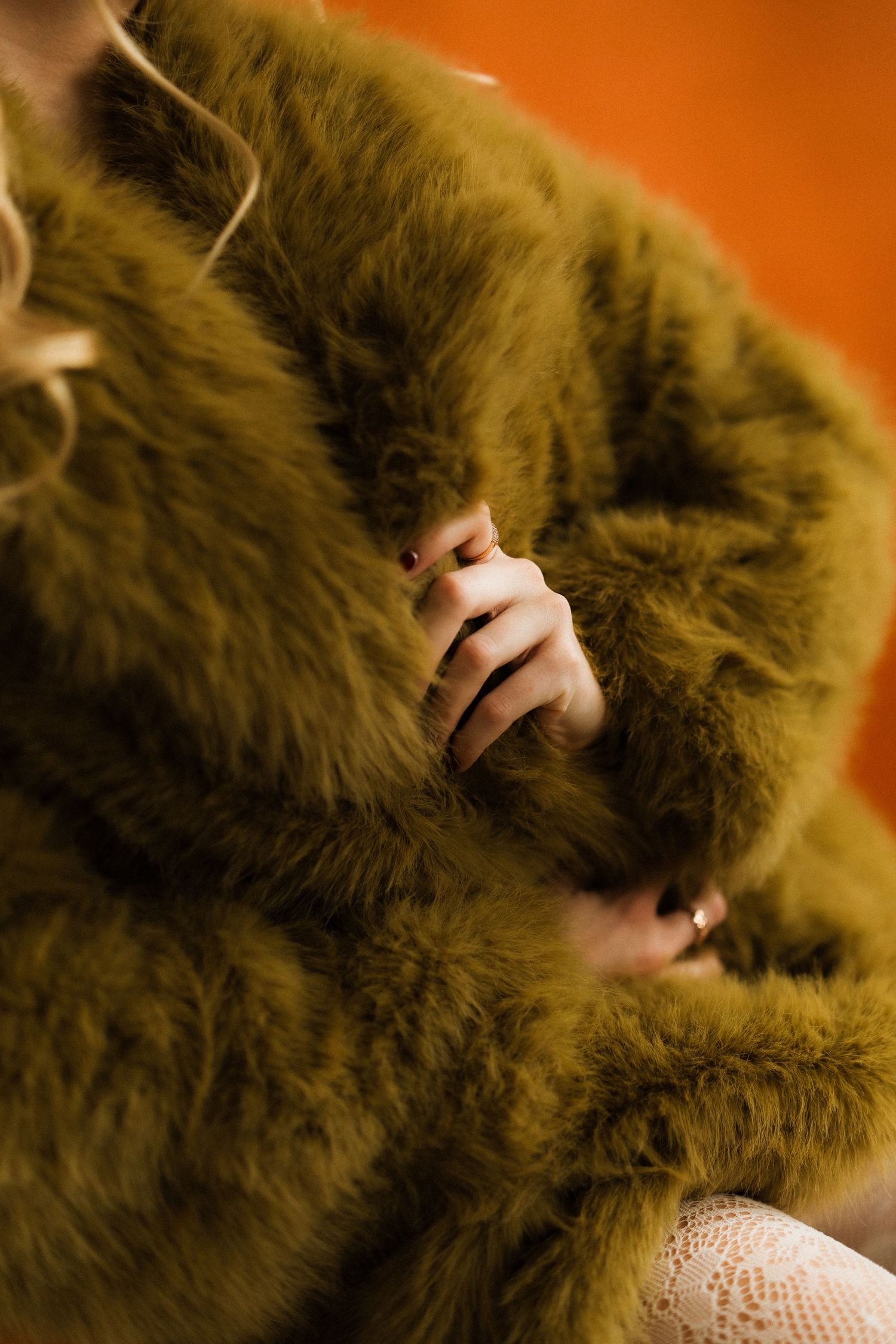 Close-up macro shots of brown fur with fingers gently touching the soft texture against an orange background.