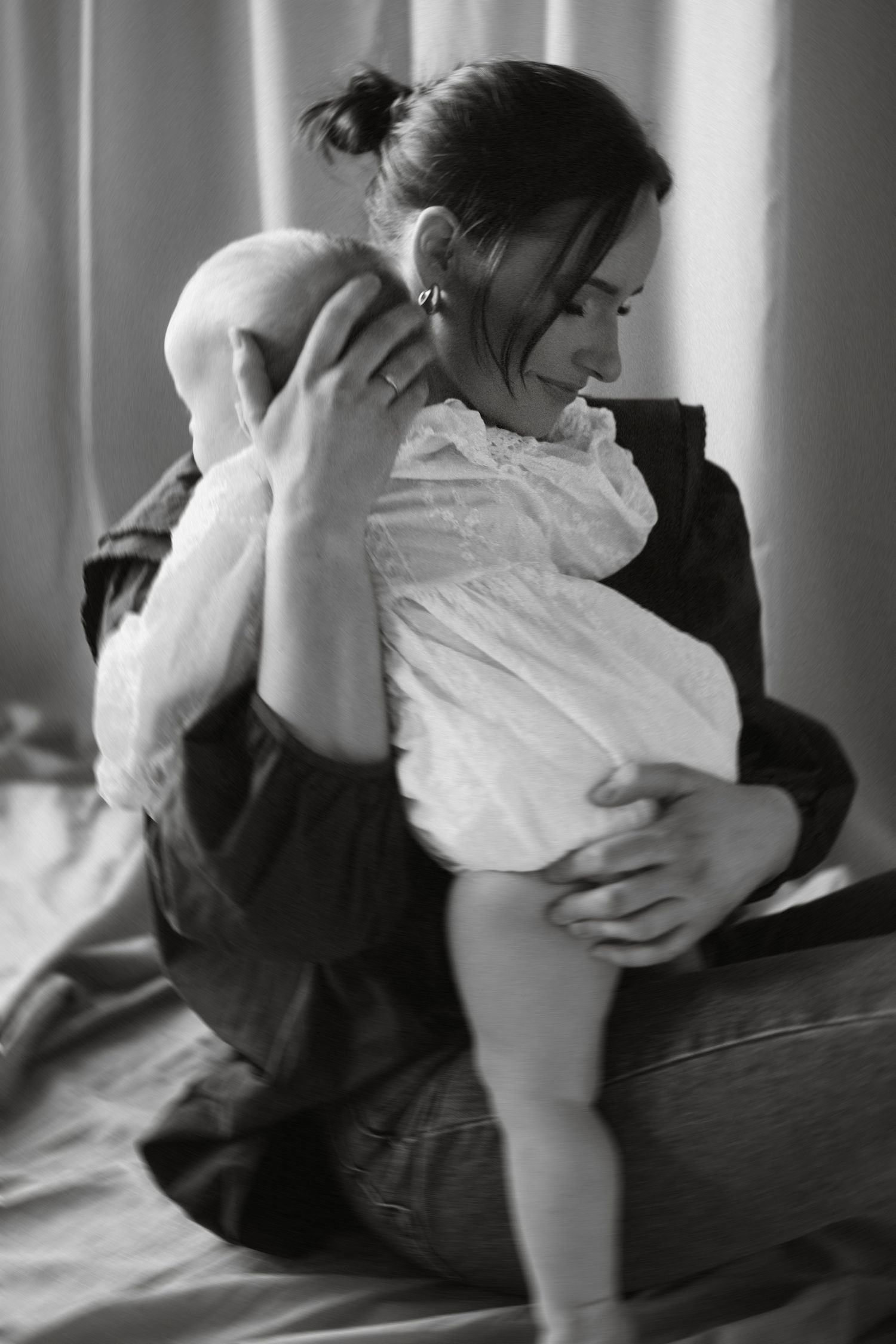 Four black and white photographs show a tender moment of a person holding a baby wrapped in white cloth.
