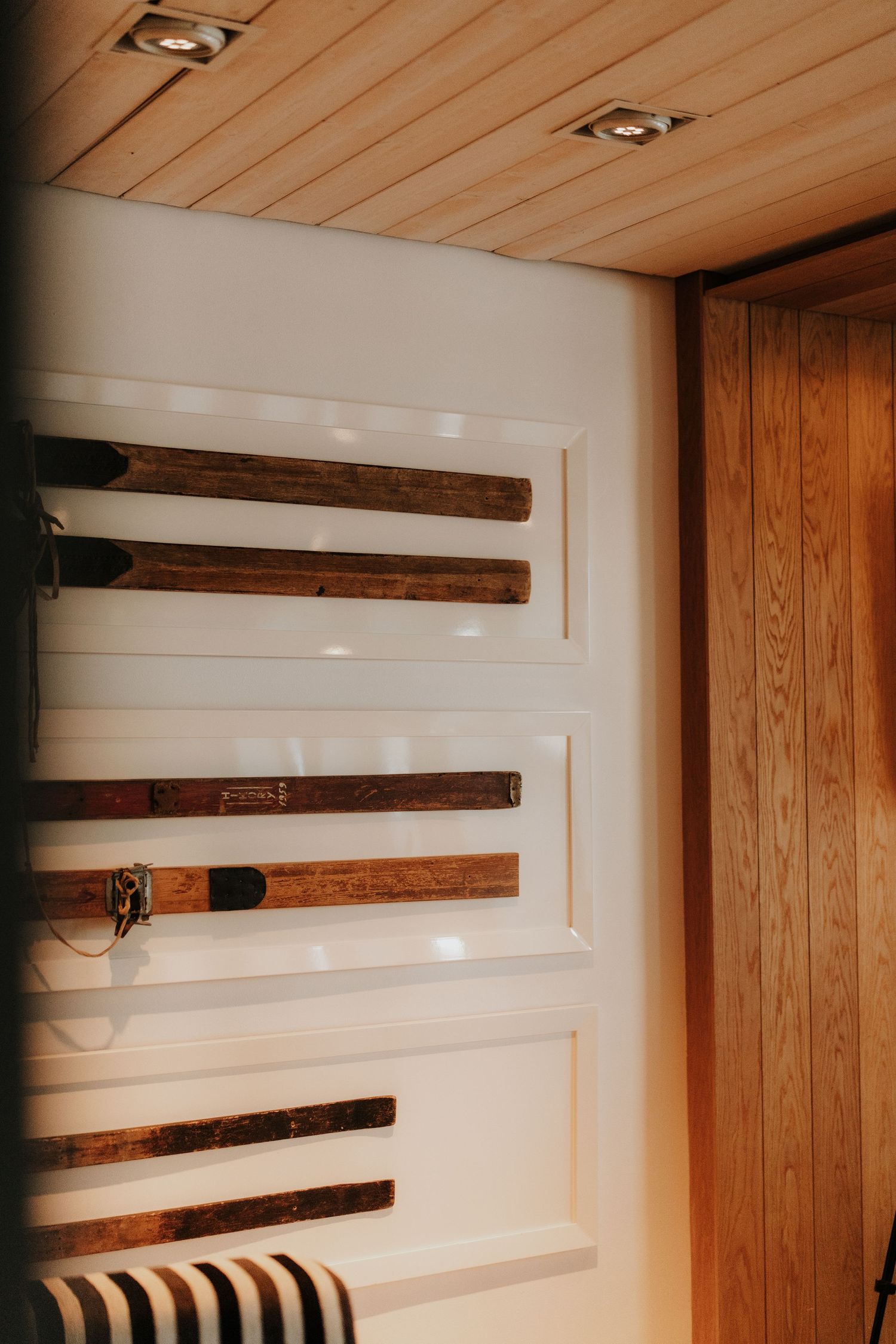 Wood beam installation progress showing multiple rustic beams being mounted on a white wall with wood paneling.