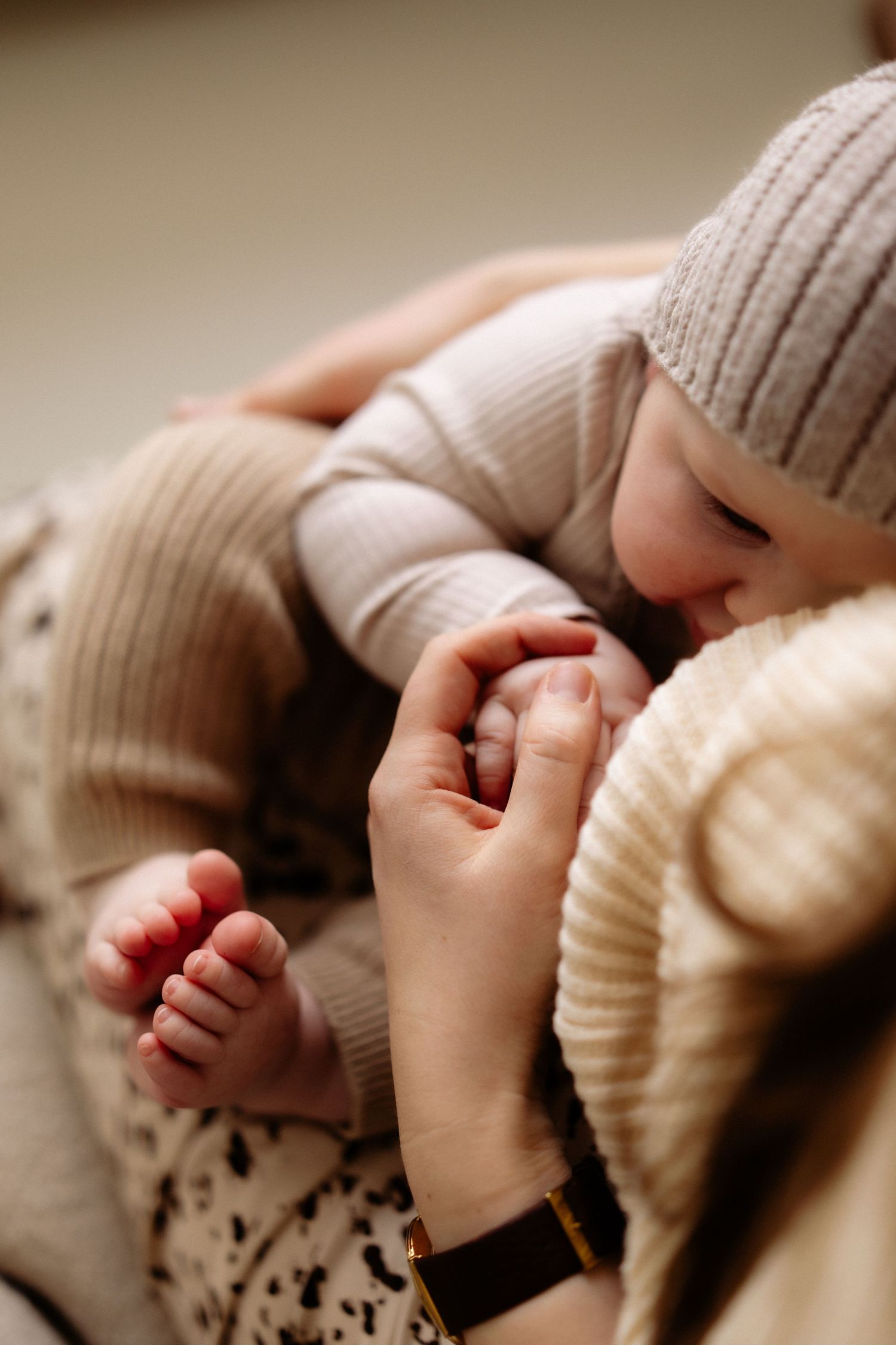 Close-up sequence of tiny baby fingers grasping soft knitted fabric in warm neutral tones.