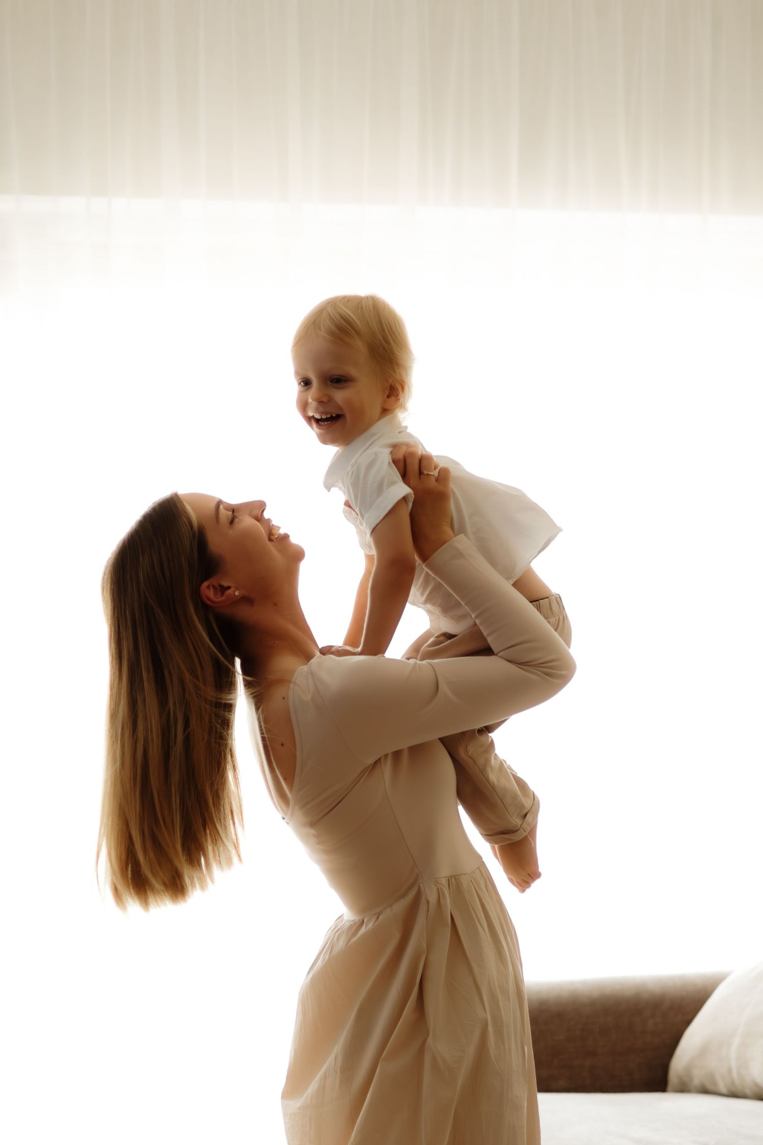 A tender moment captured in a series of photos showing a parent lifting and playing with a baby in white clothing.