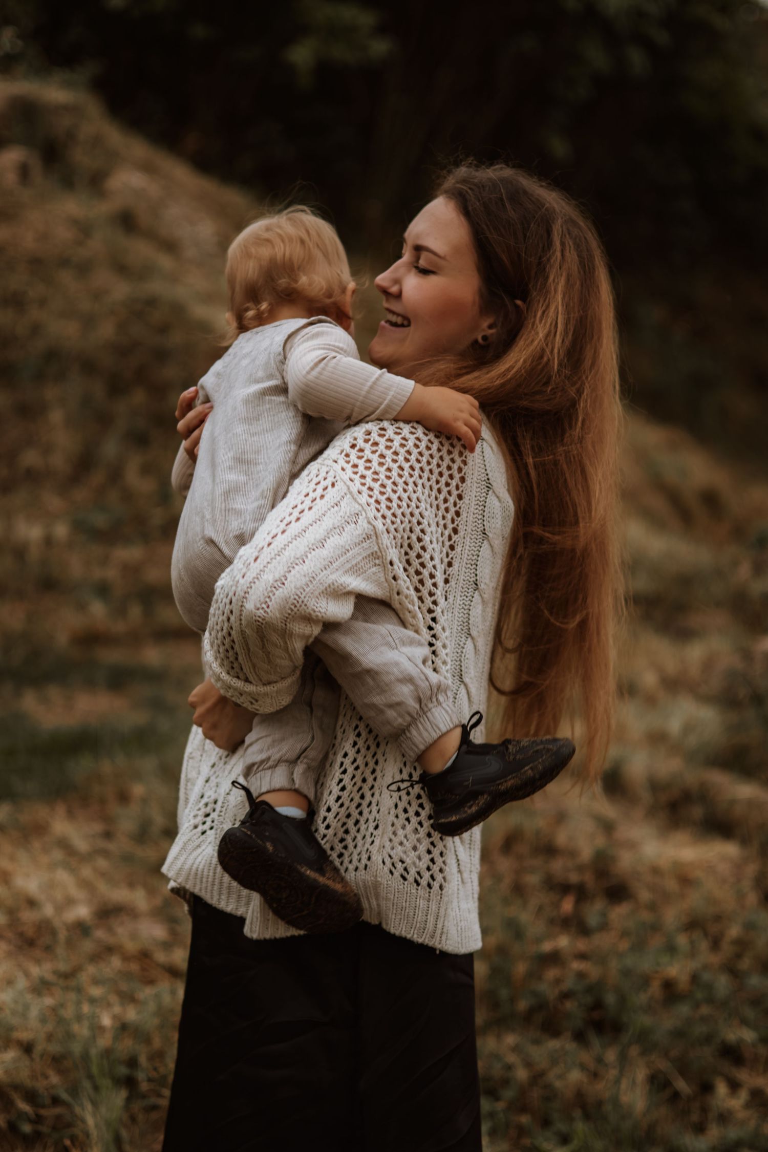 Mother and child in white knit sweaters share tender embraces in a series of intimate outdoor autumn portraits.