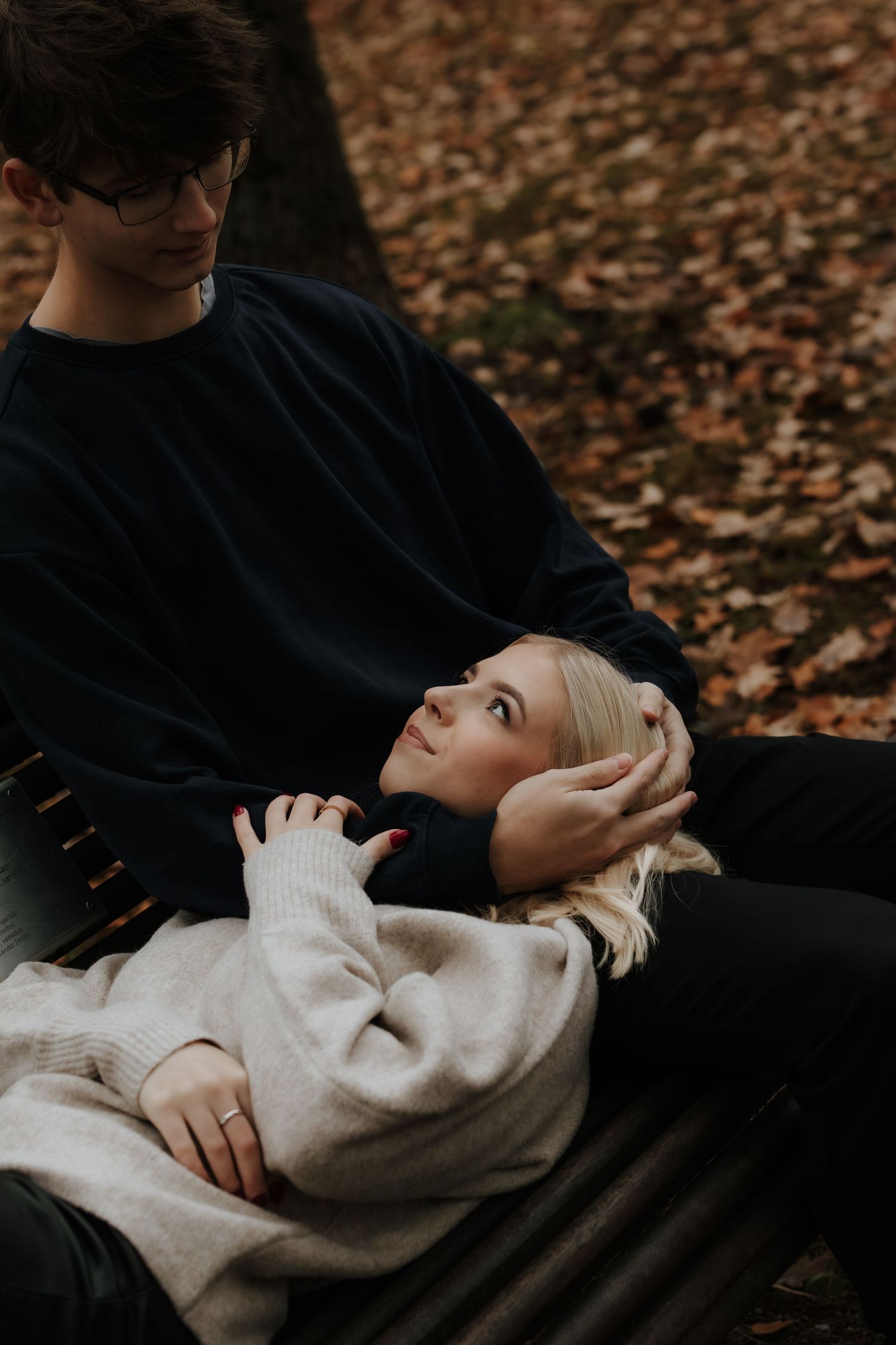 Couple in black and white outfits laying on autumn leaves share intimate moments in a romantic photoshoot sequence.