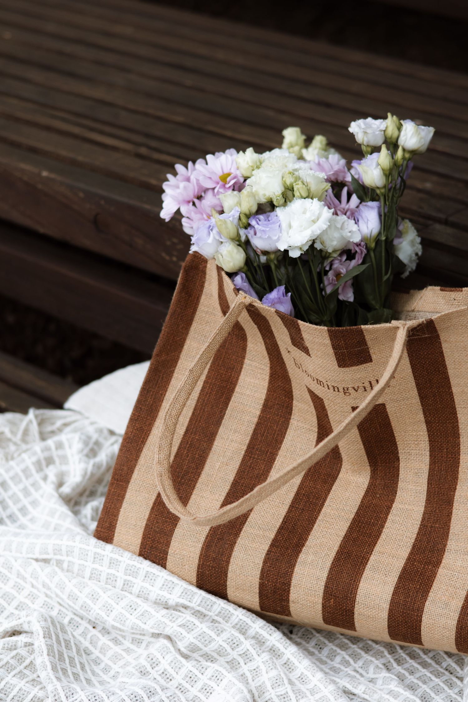 A striped brown paper bag with pink and white flowers sits on white lace fabric showing progression of different angles.