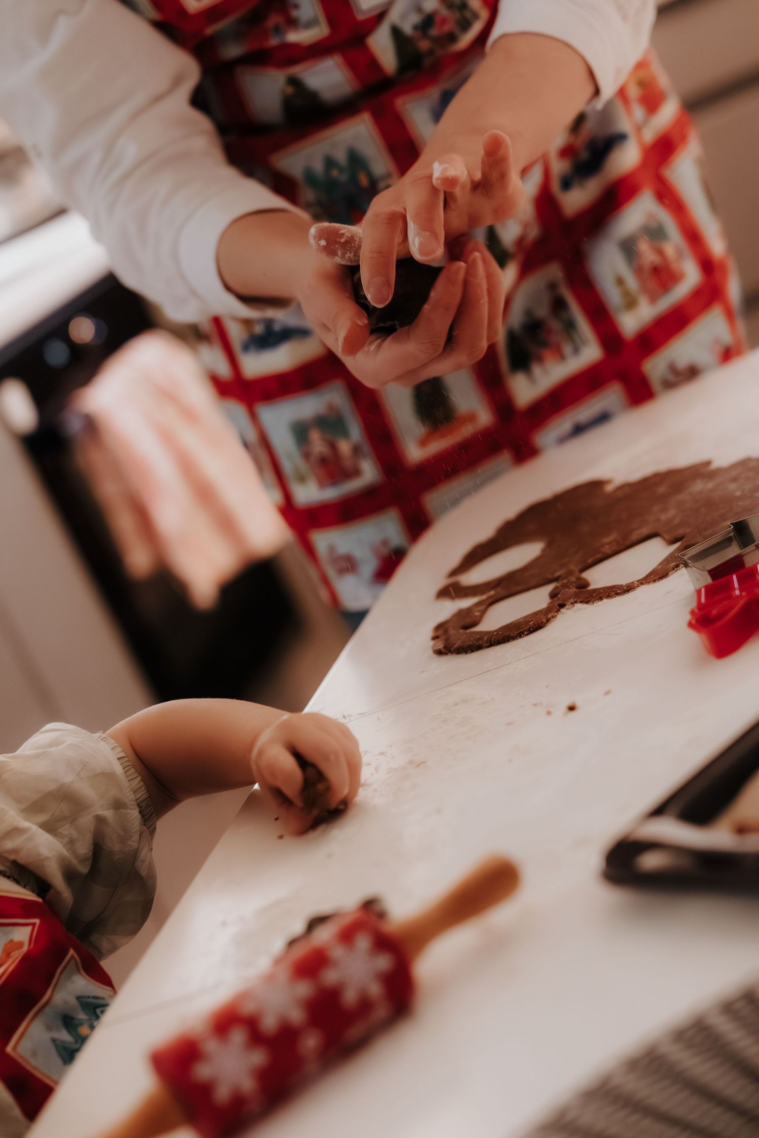 Hands working on a white surface with crafting materials and red decorative elements in a creative workshop setting.