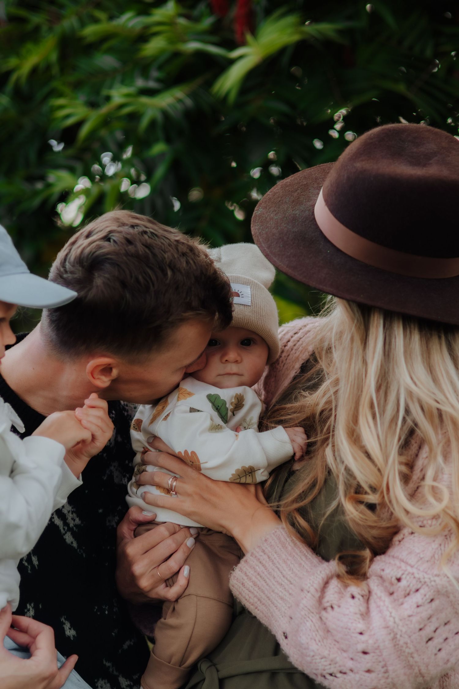 A group of people in hats laughing and embracing together outdoors in a candid moment.