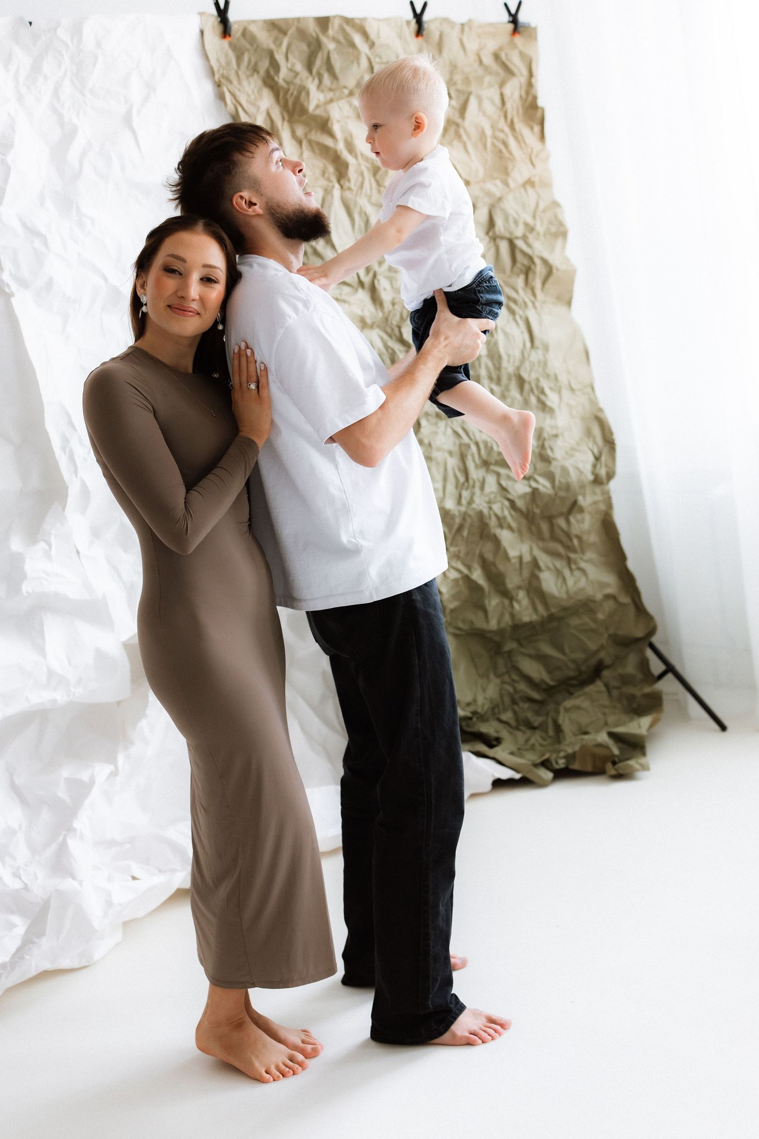A series of intimate portraits showing a couple embracing in front of a white textured backdrop.