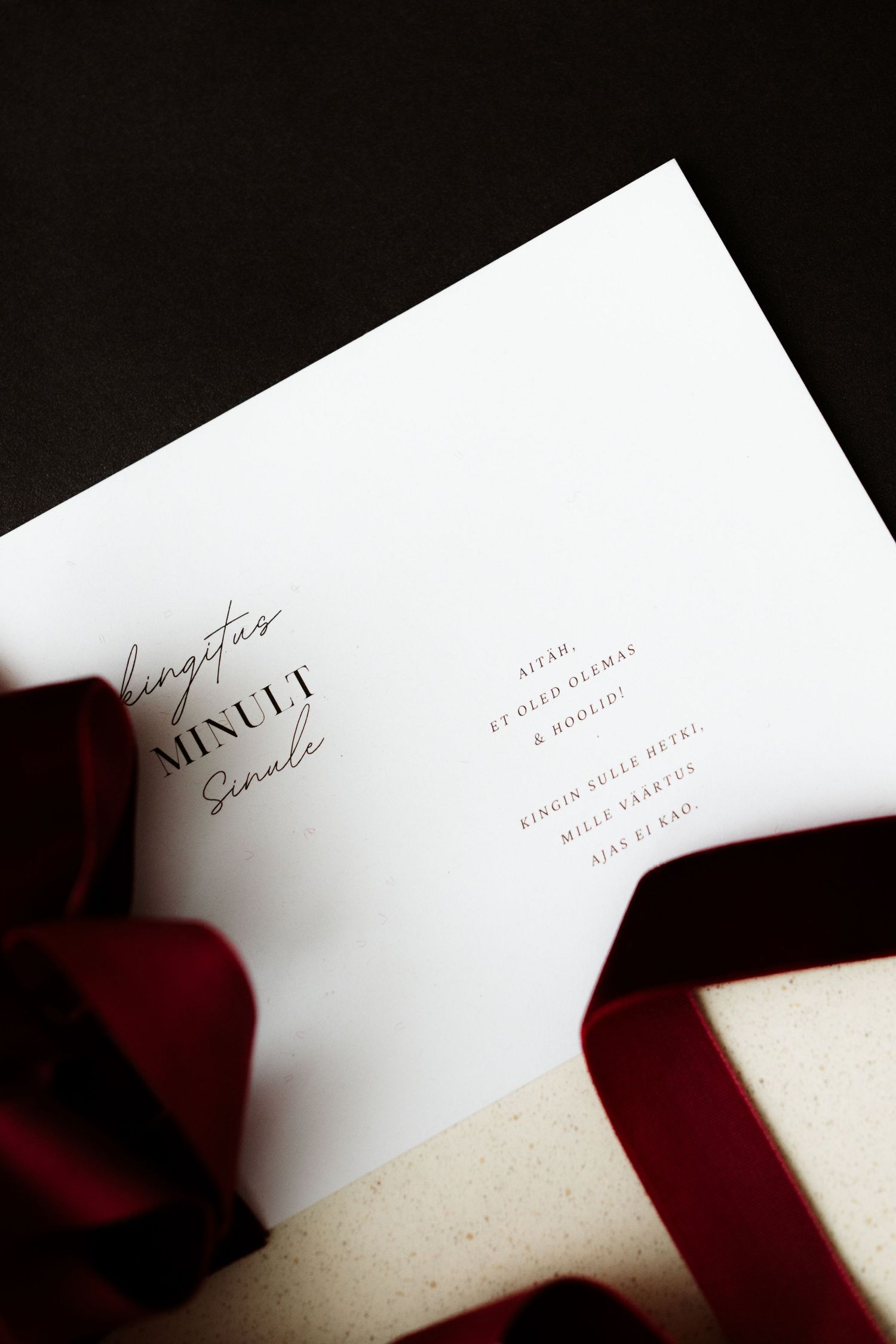Elegant white wedding menu card with minimalist design and red ribbon accent on dark background.
