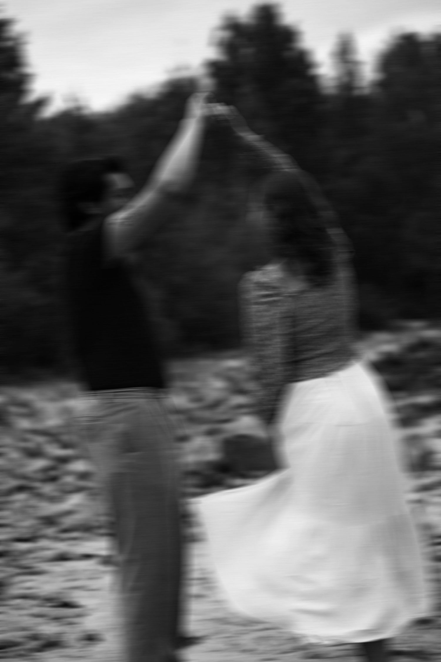 A series of black and white blurred motion photographs showing a figure in a white dress spinning outdoors.