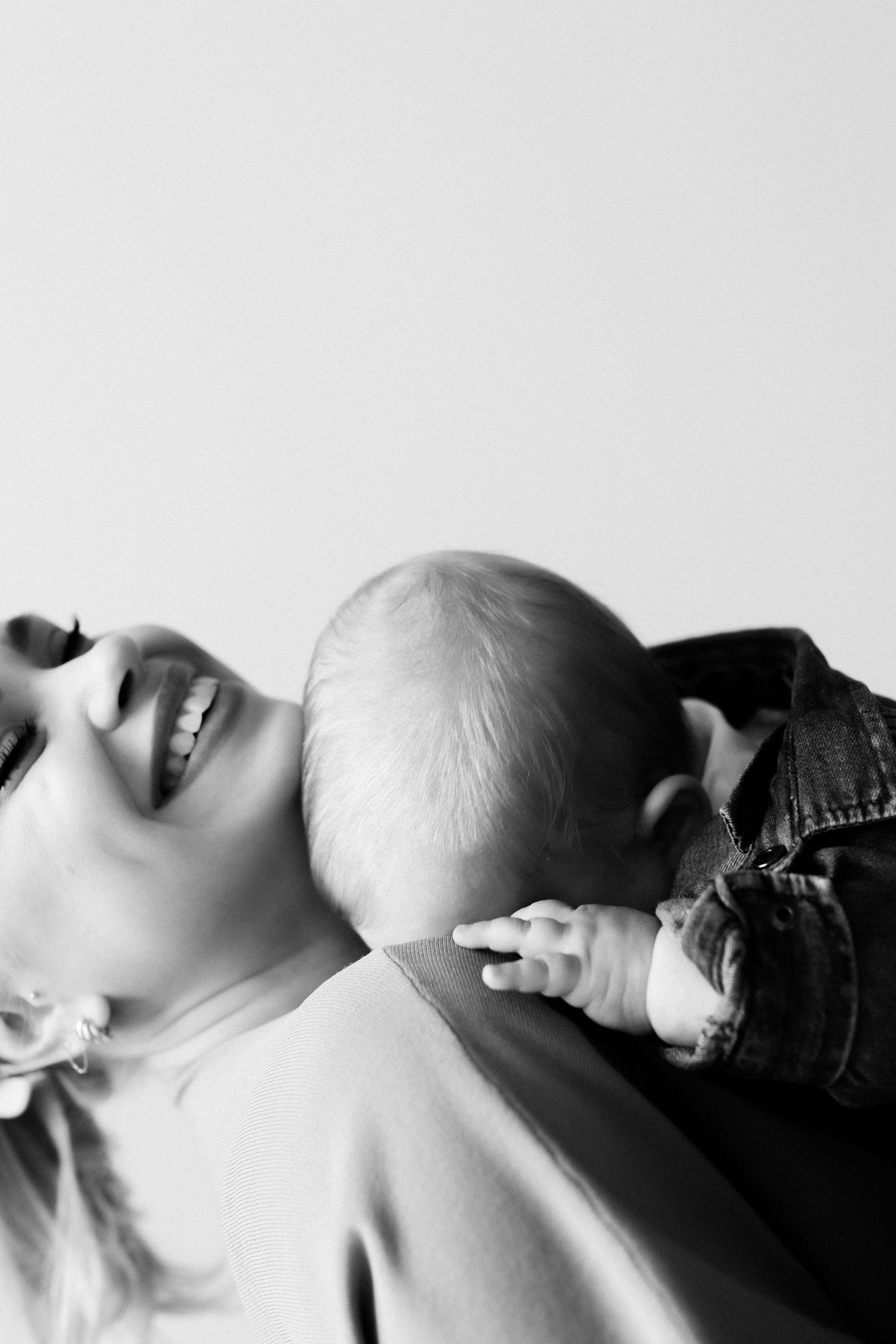 Black and white photo of a laughing mother holding her baby close, capturing a tender and joyful bonding moment.