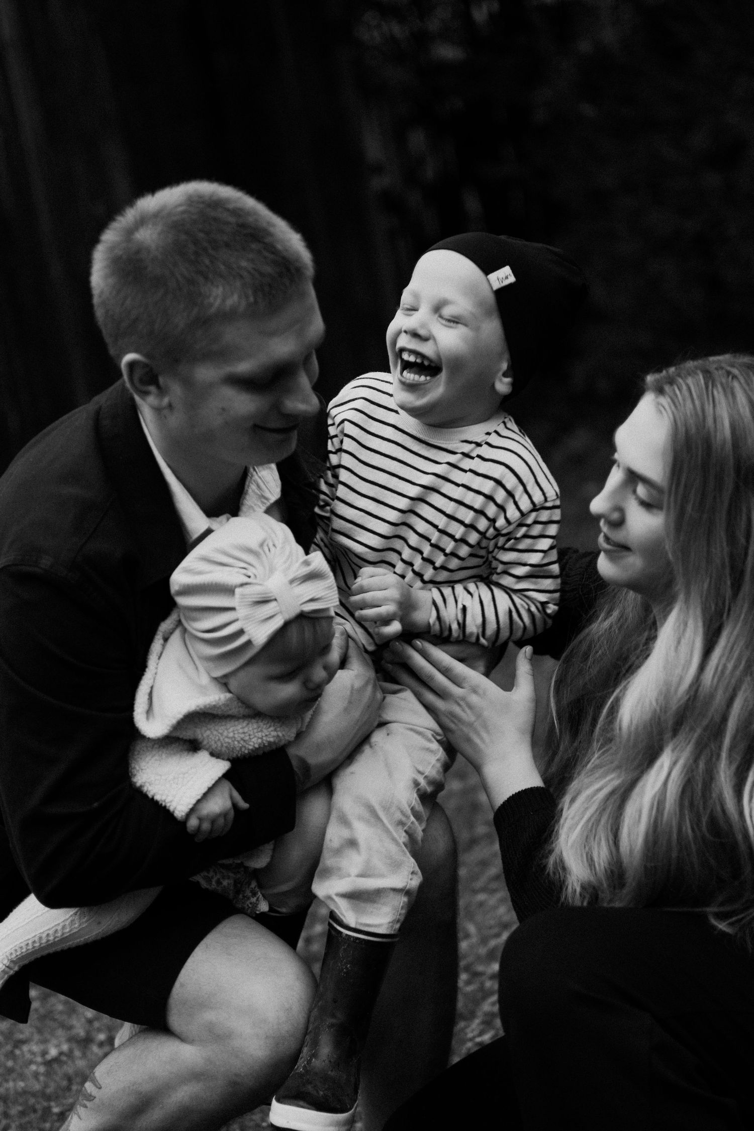 A series of black and white candid family photos showing joyful moments and interactions between parents and child.