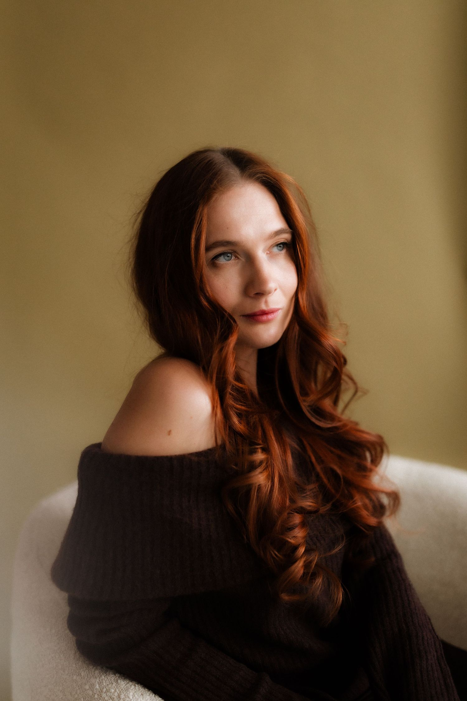 A series of artistic portrait photos showing someone with flowing red hair wearing a black sweater against a neutral wall.