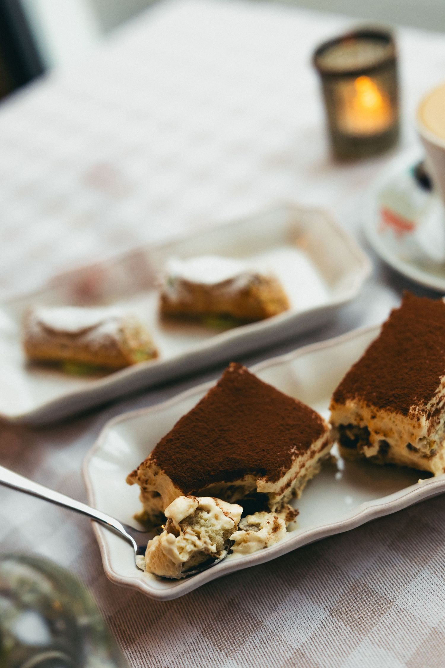 A slice of rich chocolate tiramisu dessert served on a white rectangular plate with creamy layers visible.