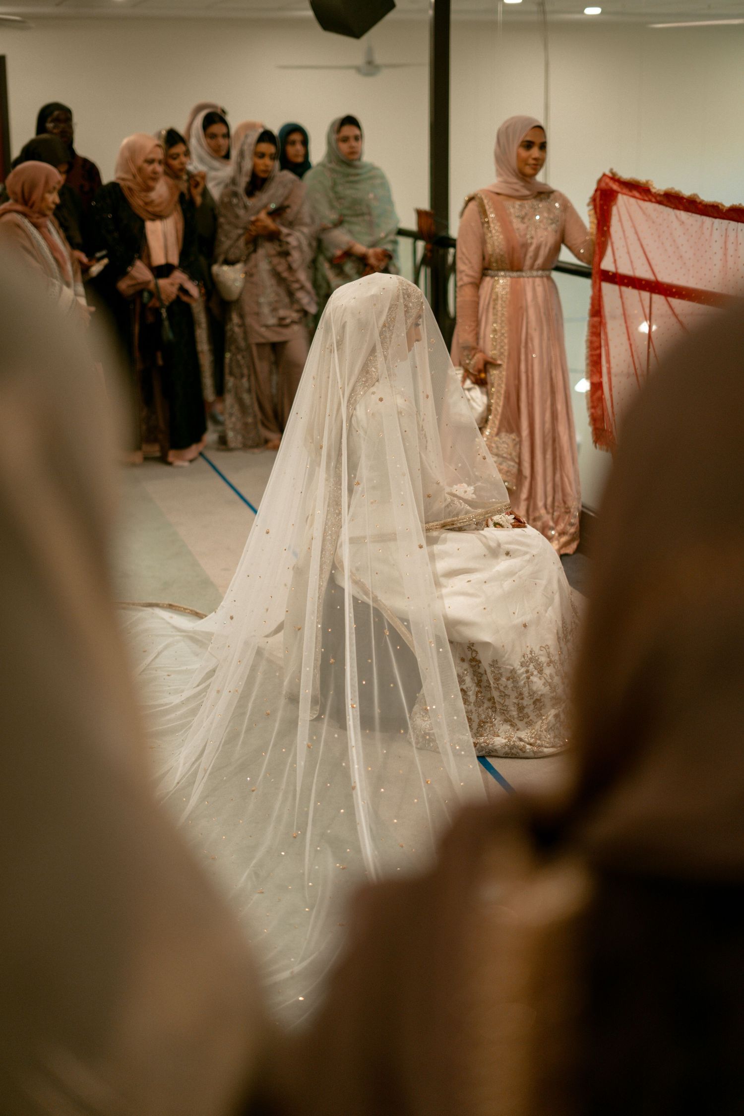 Muslim bride seated in a white embroidered gown with a pearl-adorned veil during a Nikah ceremony.