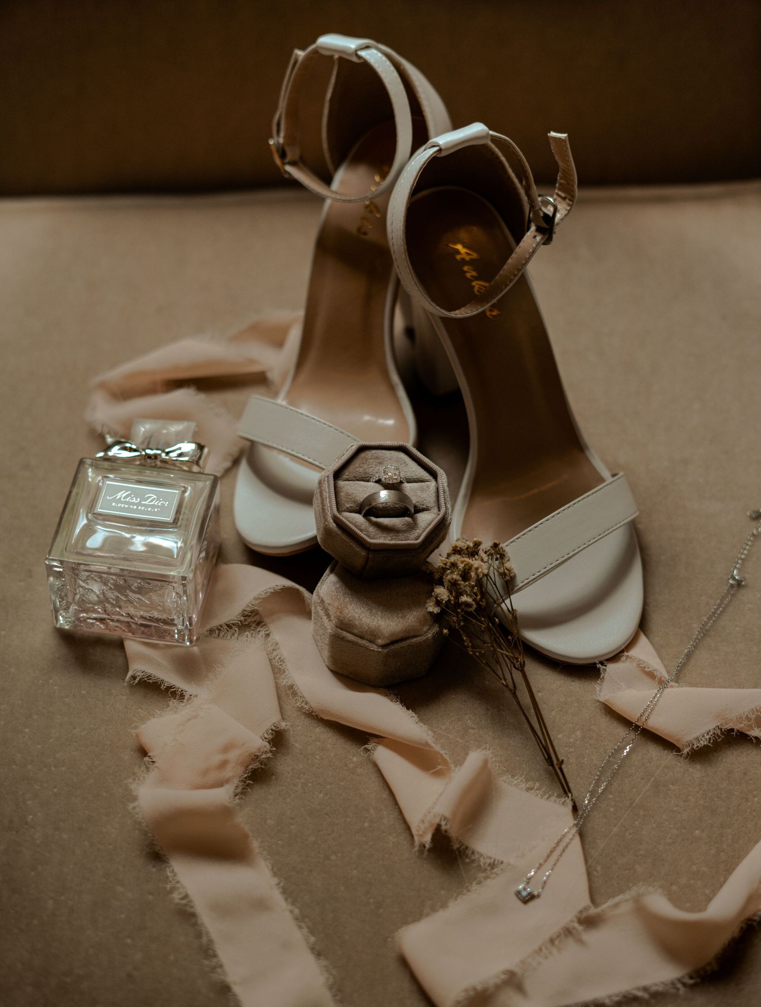 Bridal flat lay with nude heels, diamond ring in velvet box, perfume, and silk ribbons.