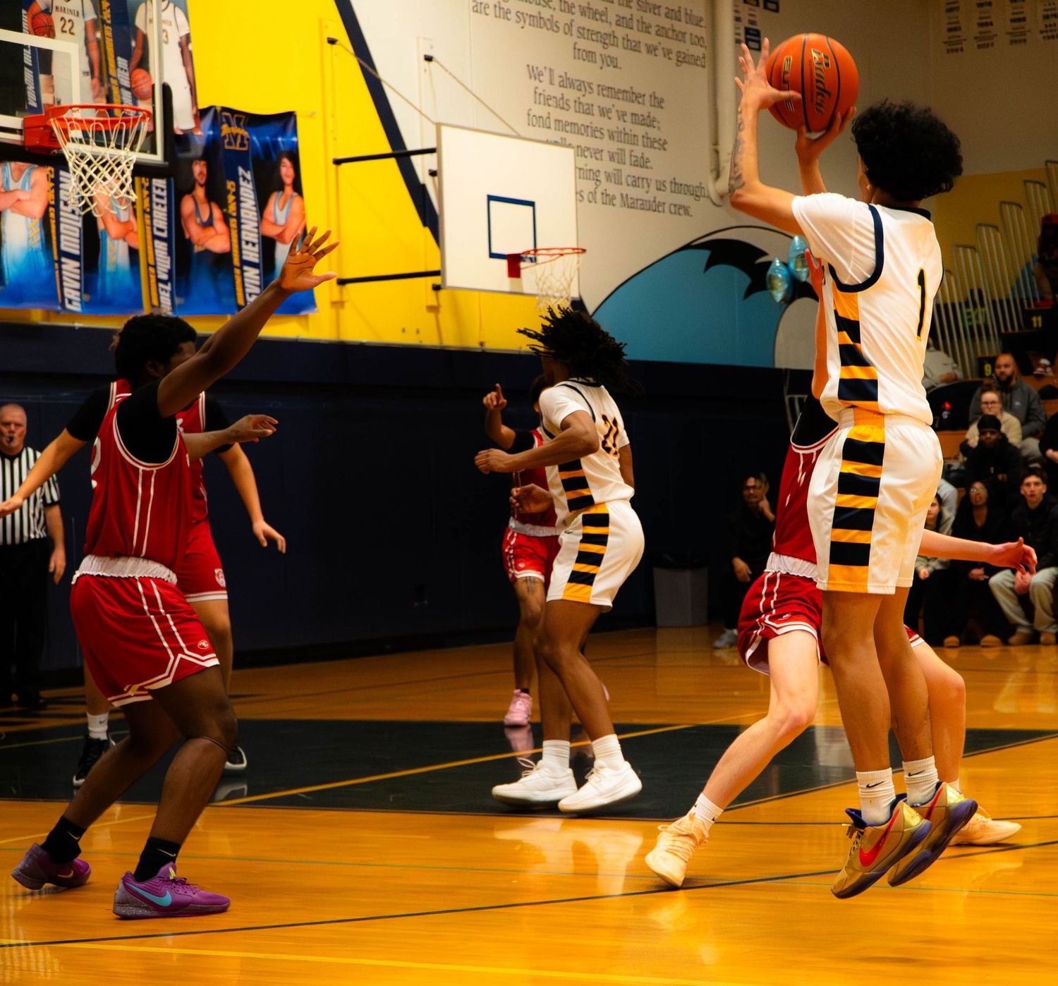 Mariner number 1 jumps to shoot over defenders during a high school basketball game.