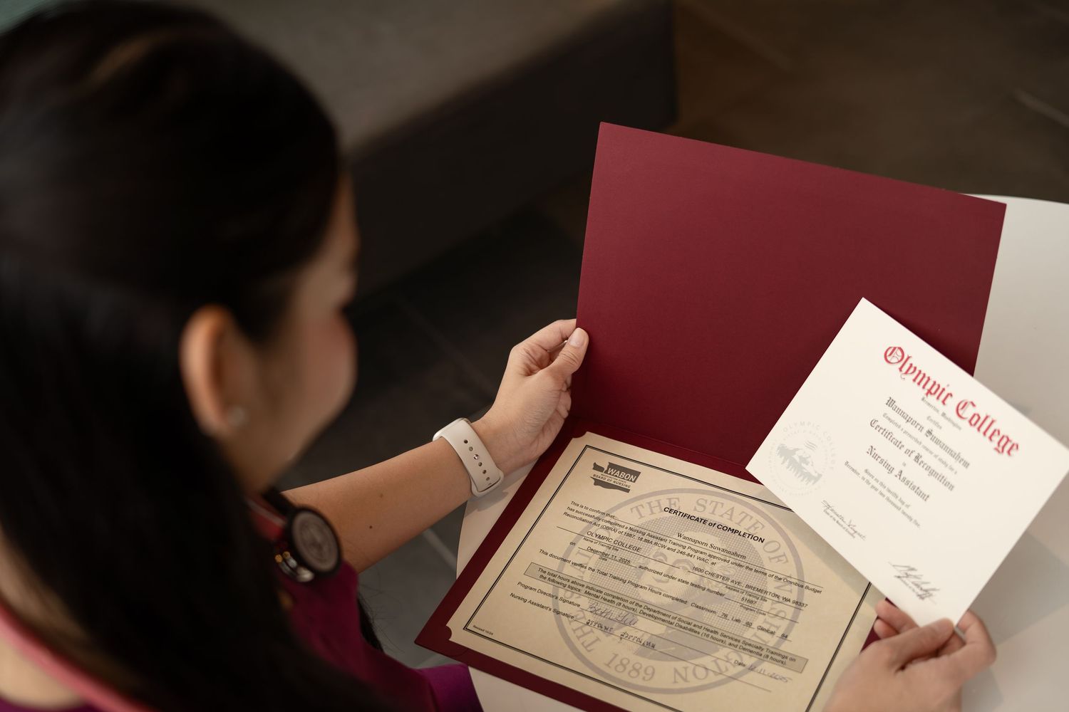 Nursing graduate reviewing diploma and certificate from Olympic College.