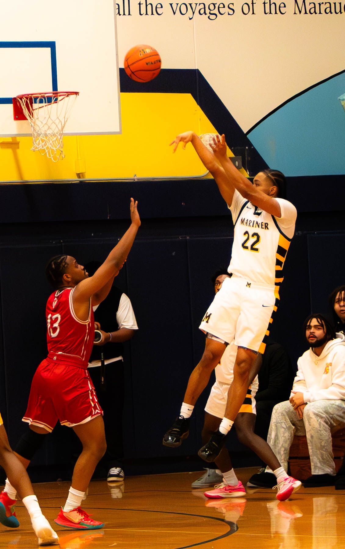 Player #22 in white Mariner jersey shoots over defender #33 in red during high school basketball game.