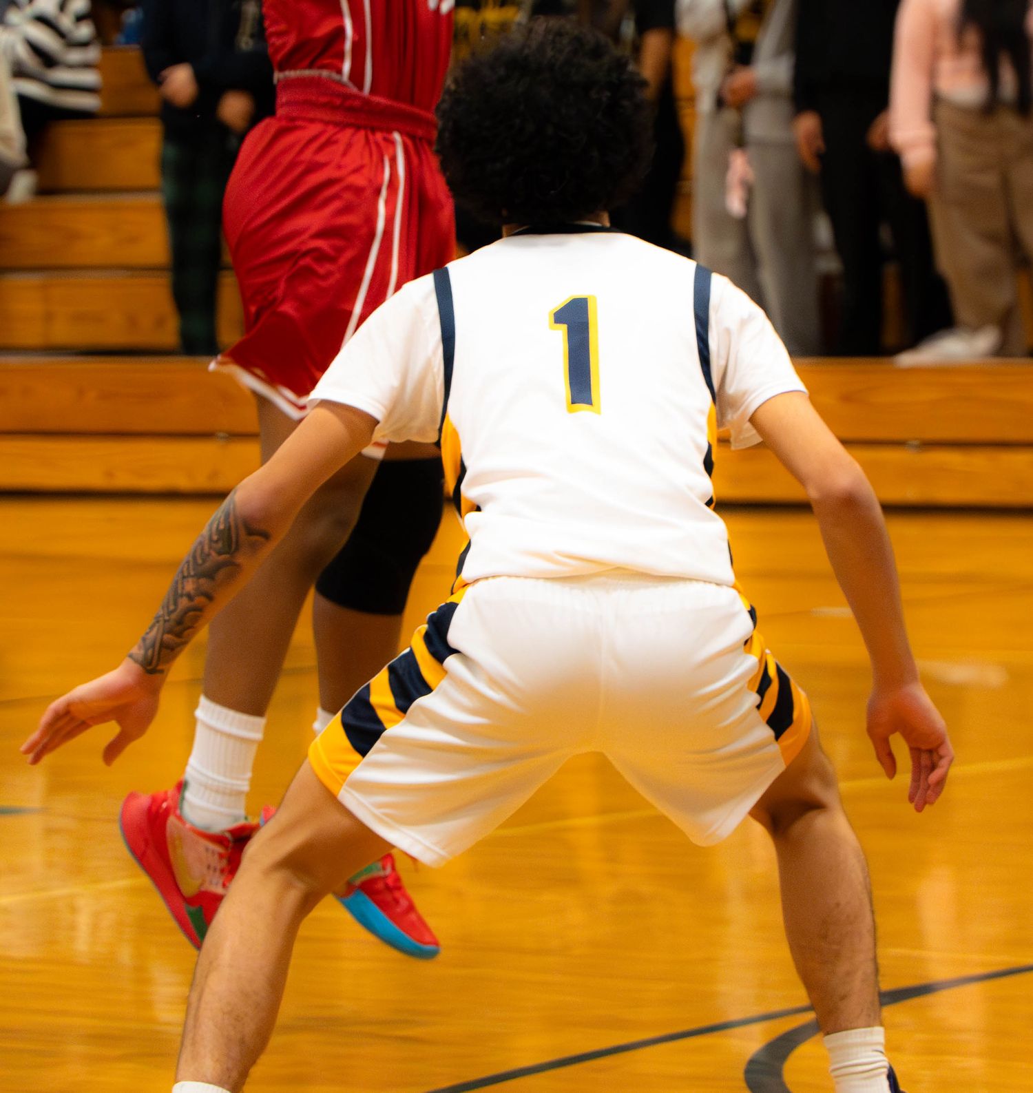 Mariner number 1 plays defense against a red-uniformed opponent during a high school basketball game.
