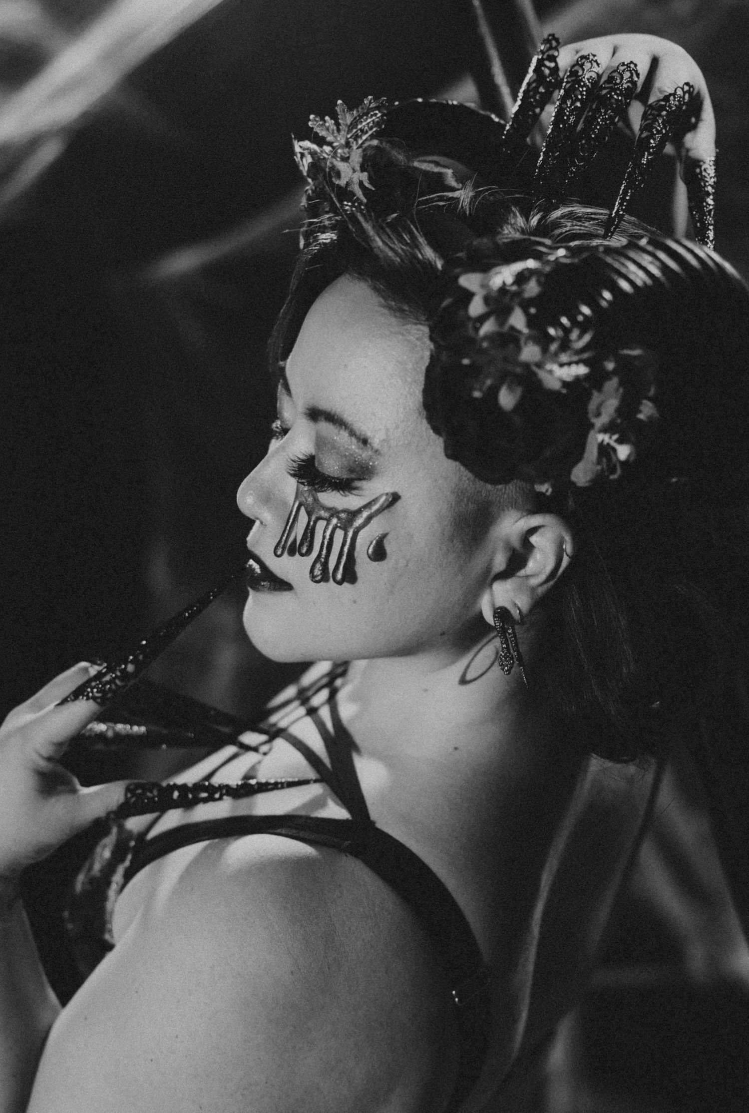 Black and white portrait of a performer with elaborate spider crown and artistic dripping eye makeup.