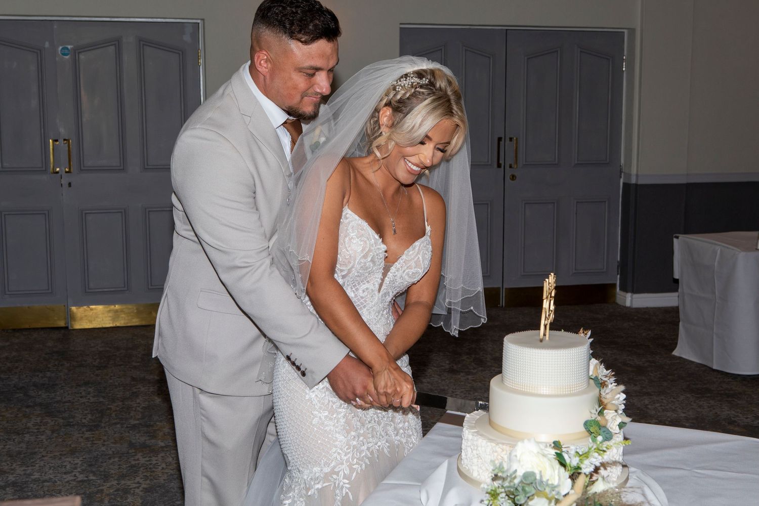 Bride and groom cutting their white wedding cake together at their wedding reception.
