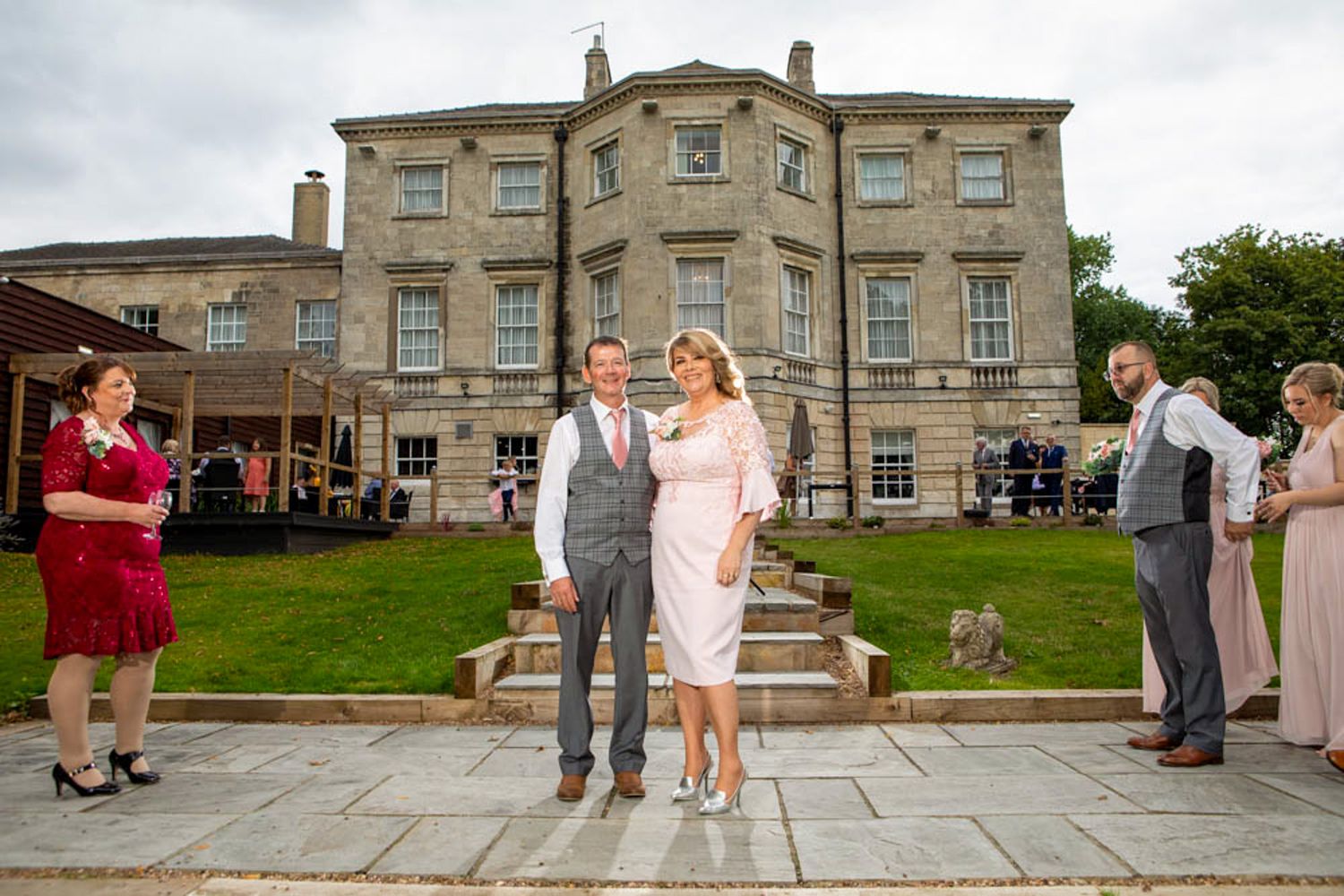 Couple in formal attire posing outside a grand Georgian manor house during a wedding reception. Aston Hall Hotel.