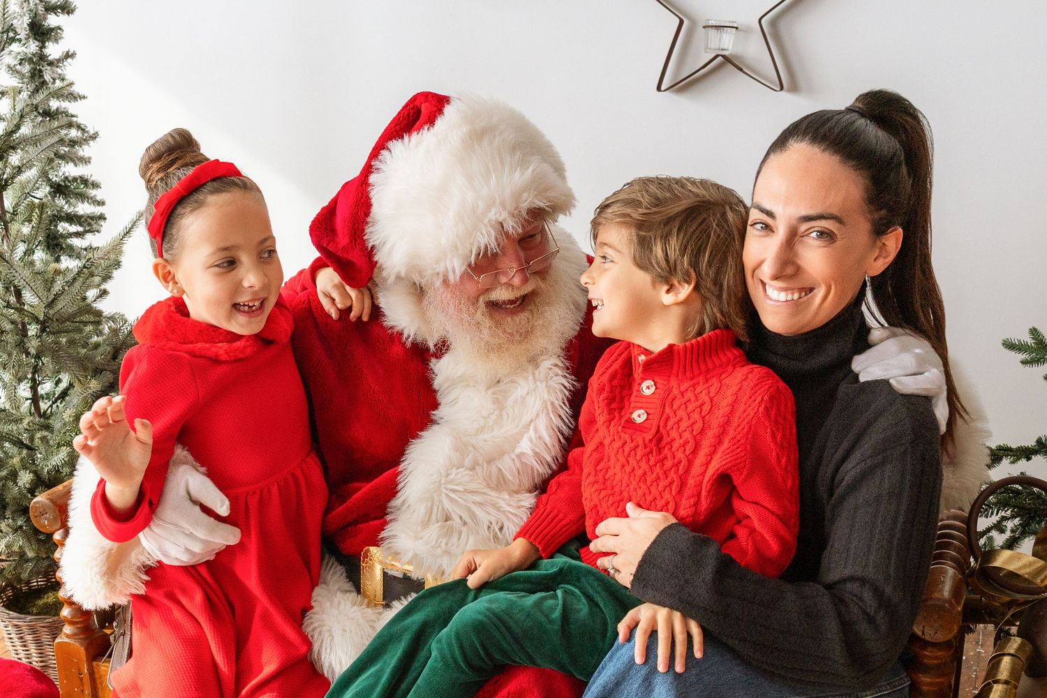 Family with two children laughs joyfully with Santa Claus during festive Christmas photo session.