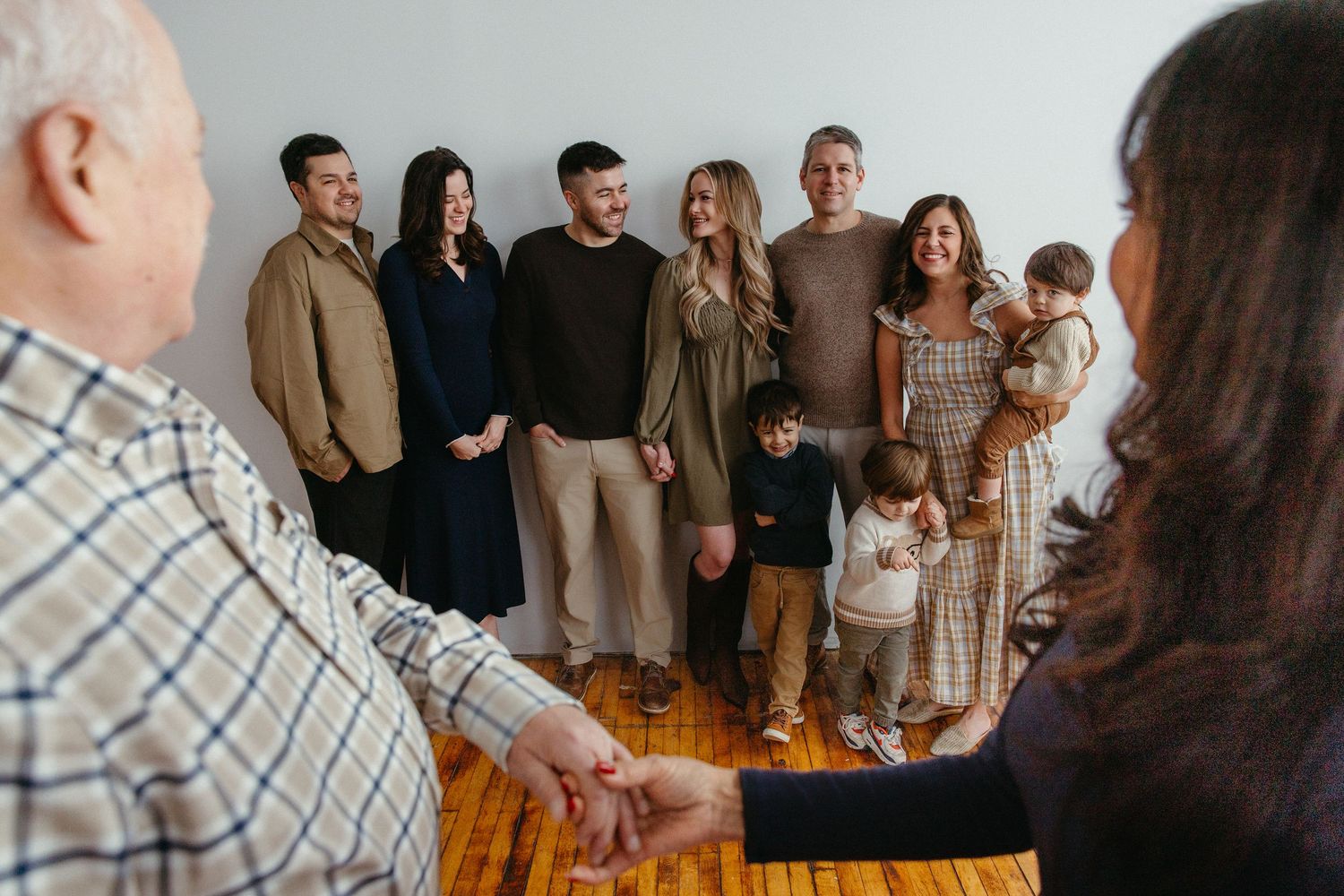 Extended multigenerational family group posing together indoors during a professional family portrait session.