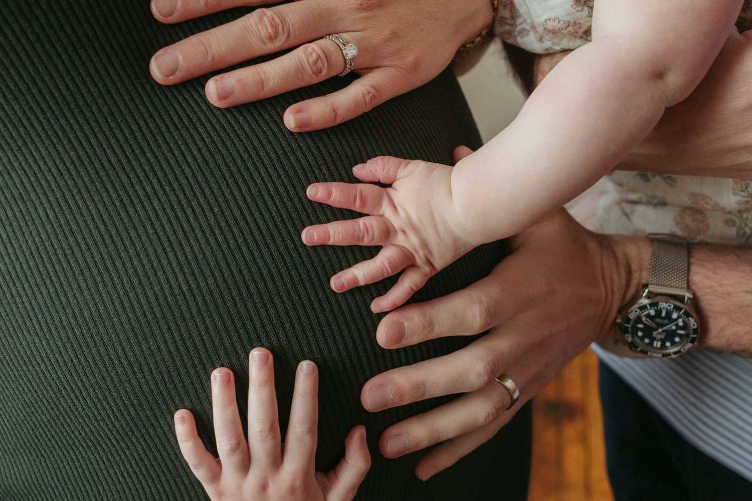 Hands resting together on mother's pregnant belly, excited for baby sibling to arrive.