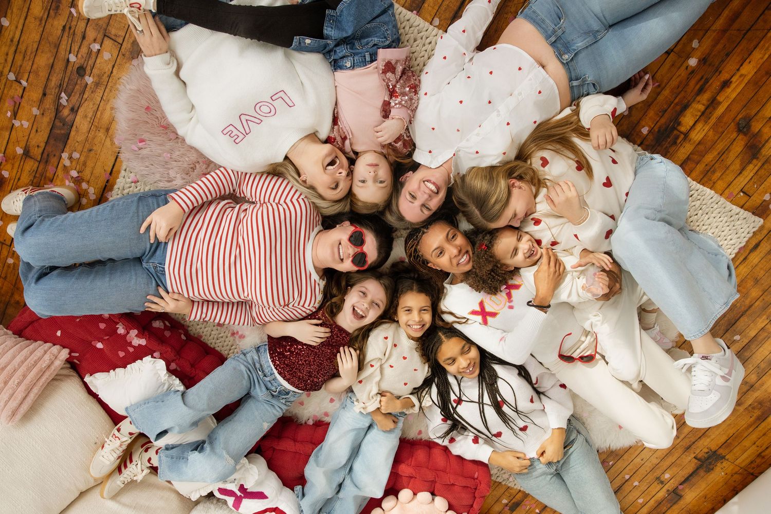 Overhead view of diverse group of girls lying in a circle on colorful rugs.