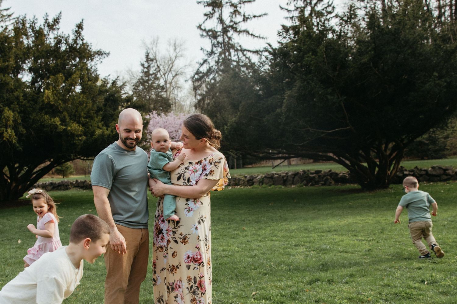 Happy family with children playing outdoors in lush green park setting.
