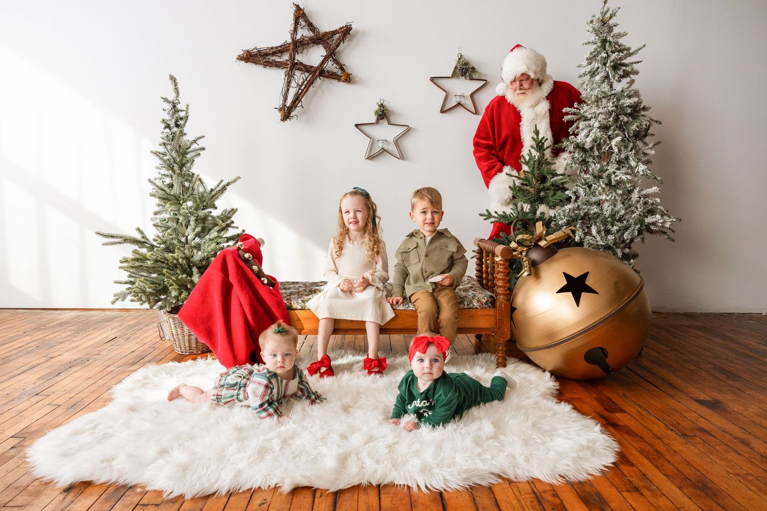 Four young children posing with Santa Claus in a beautifully decorated Christmas studio photography setting.