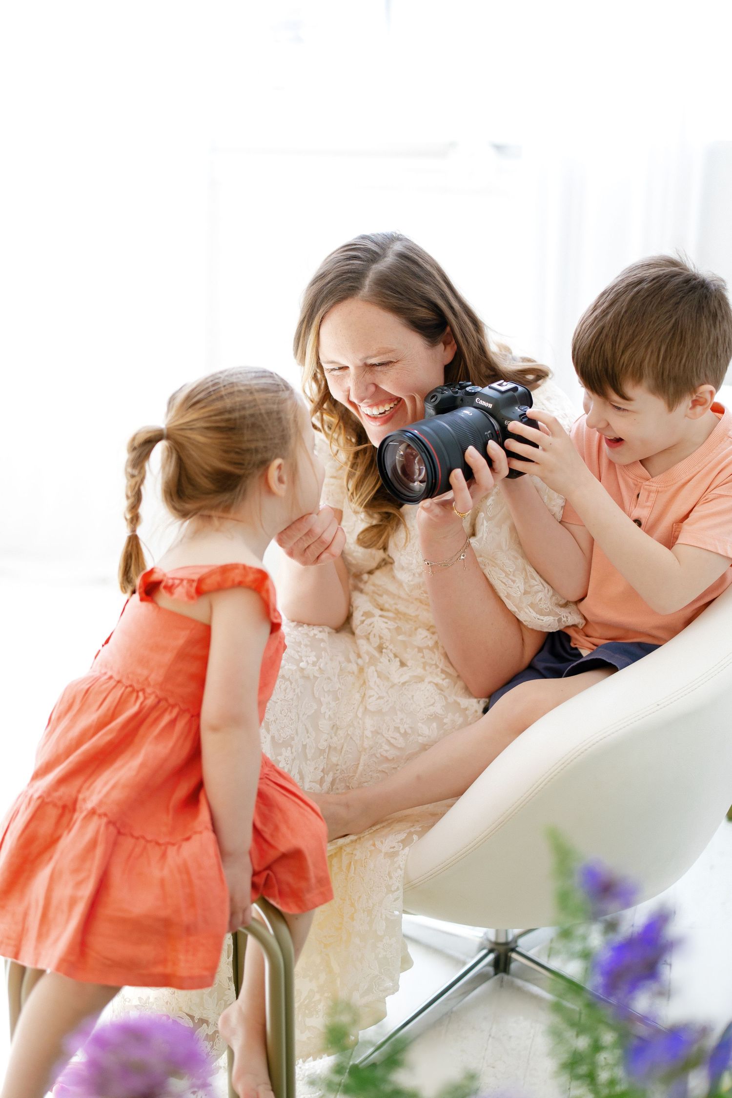 Hilary Mauro laughing with two children looking at camera in bright white studio.