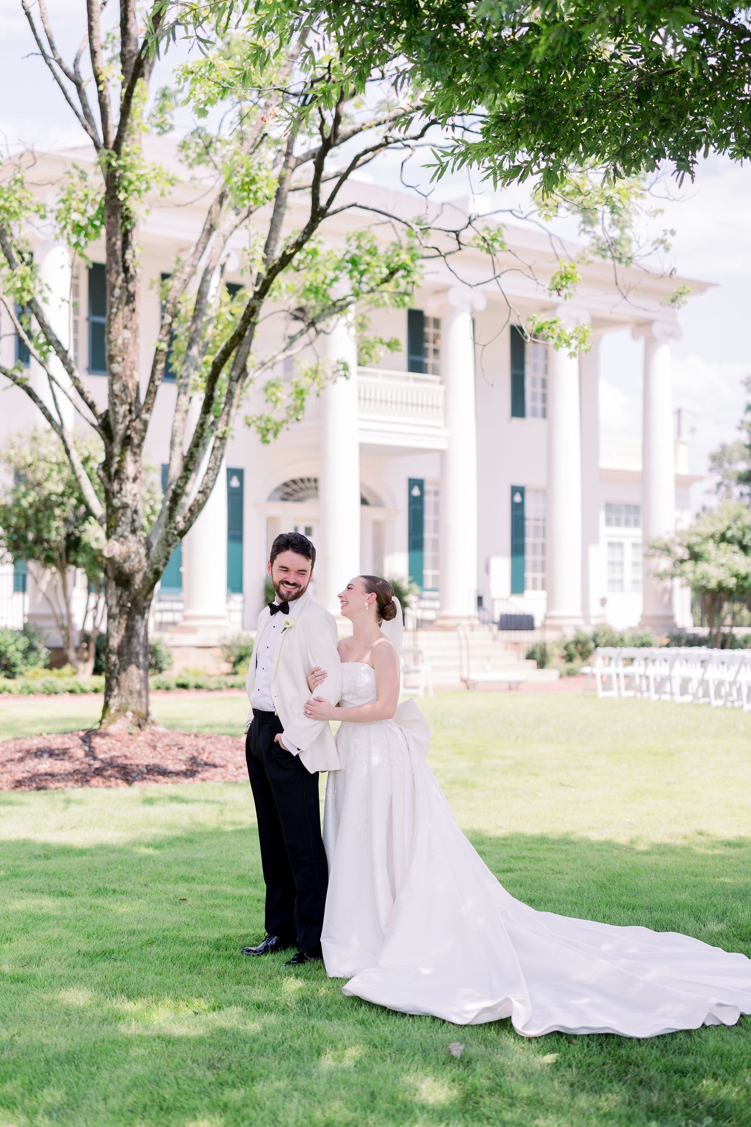 Romantic wedding photos taken on a grand white columned estate with lush green trees.