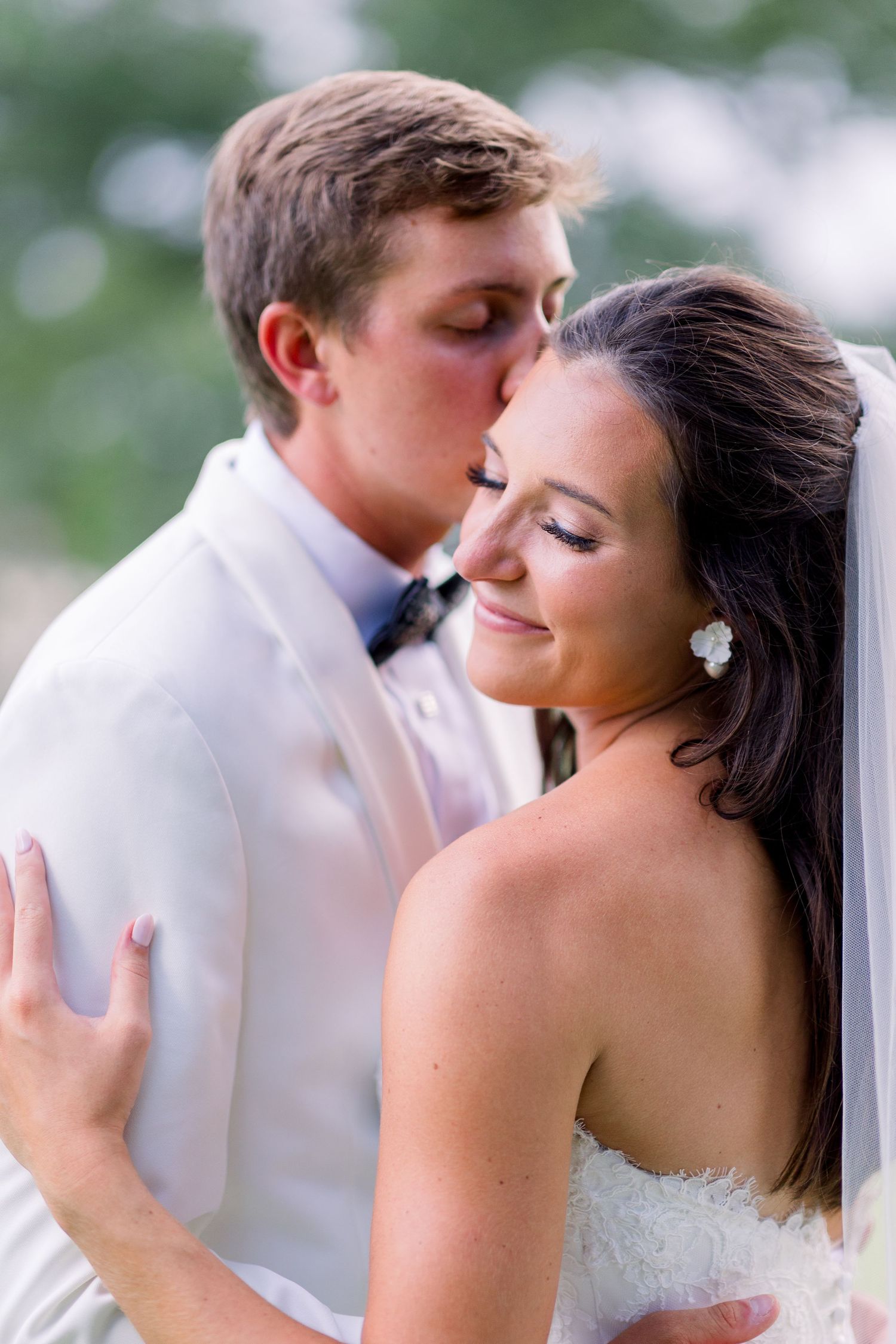 A tender moment between newlyweds sharing an intimate embrace outdoors.