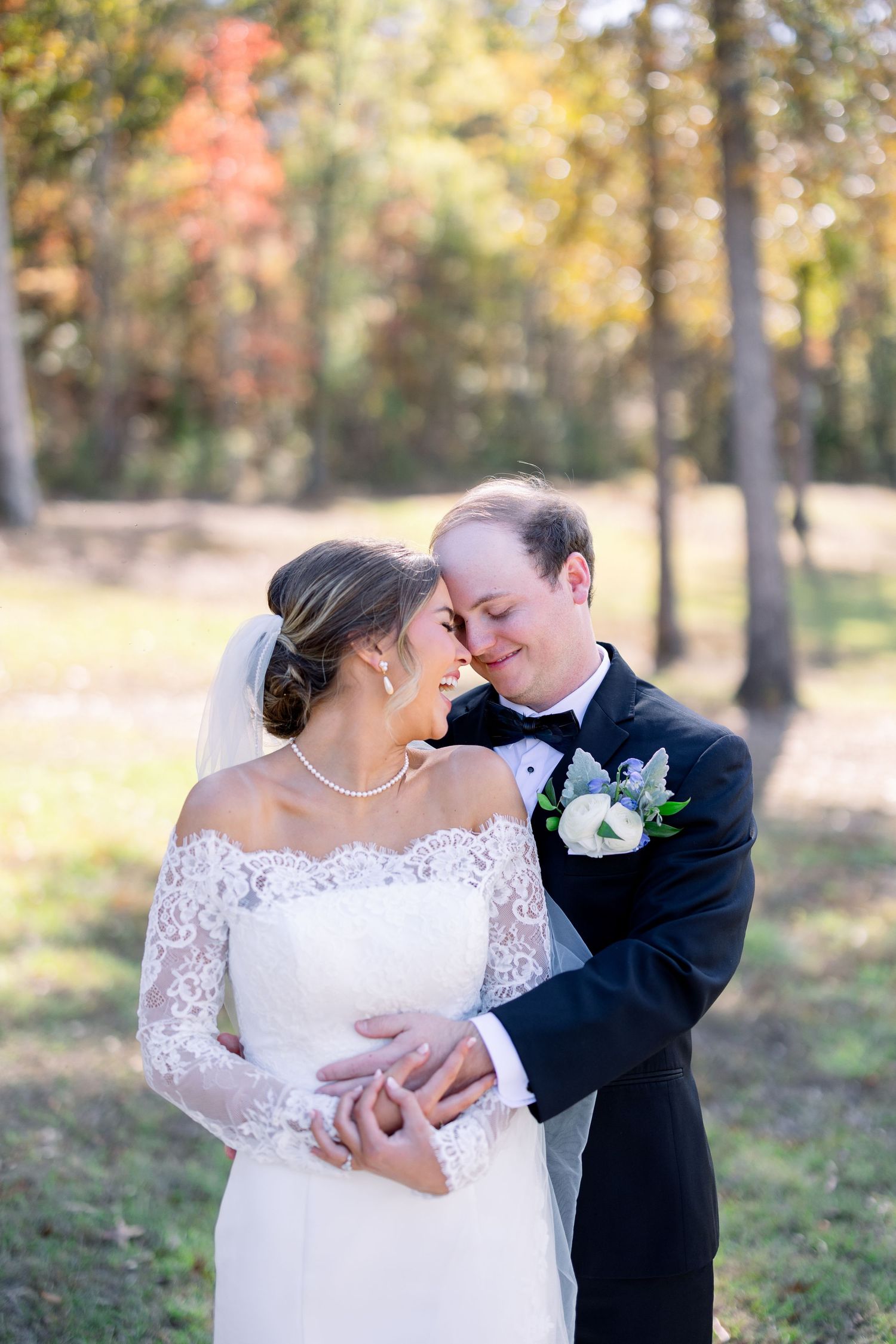 Romantic wedding couple shares intimate moments in a sunlit autumn forest with golden foliage.