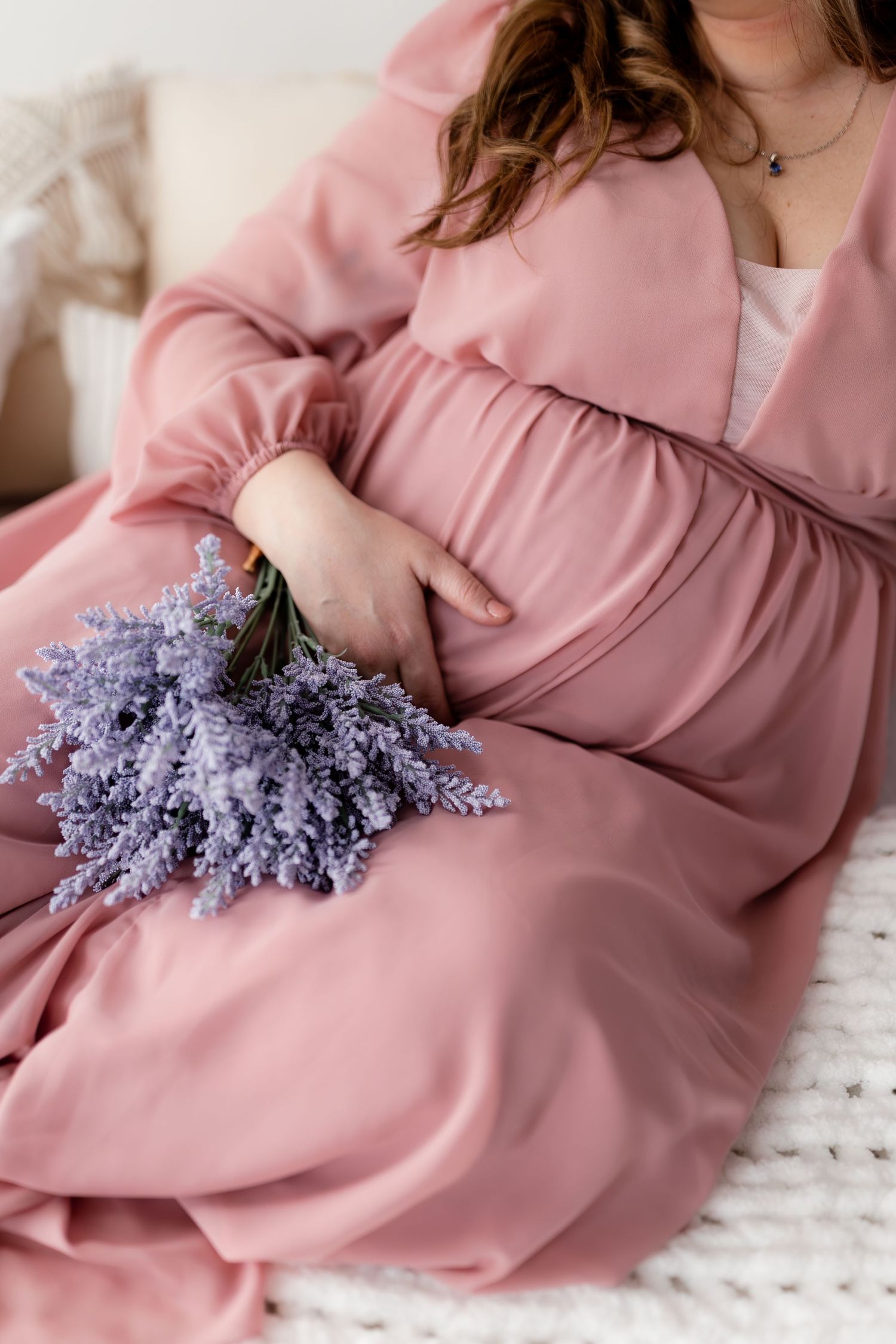 Person wearing pink dress lying down with purple lilac flowers.