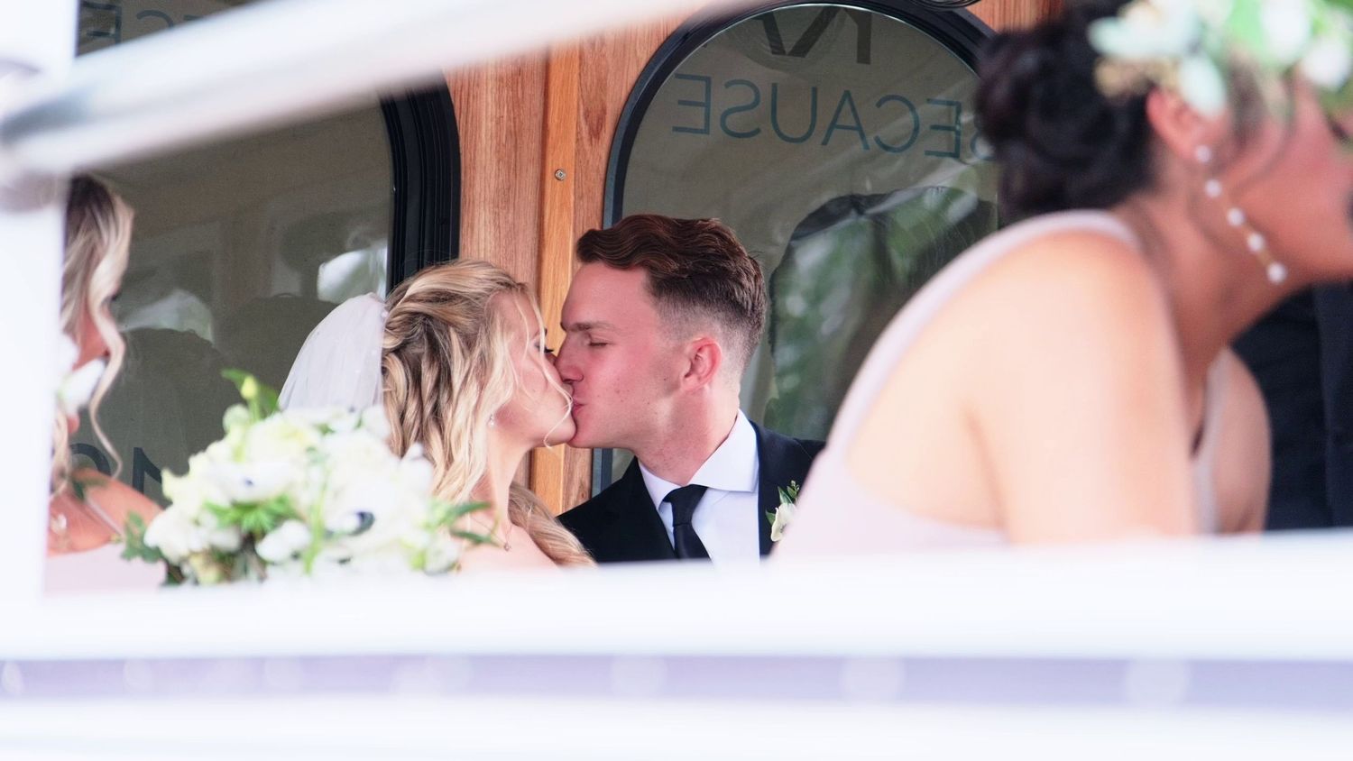 Romantic moment captured between newlyweds in vintage vehicle during wedding celebration.