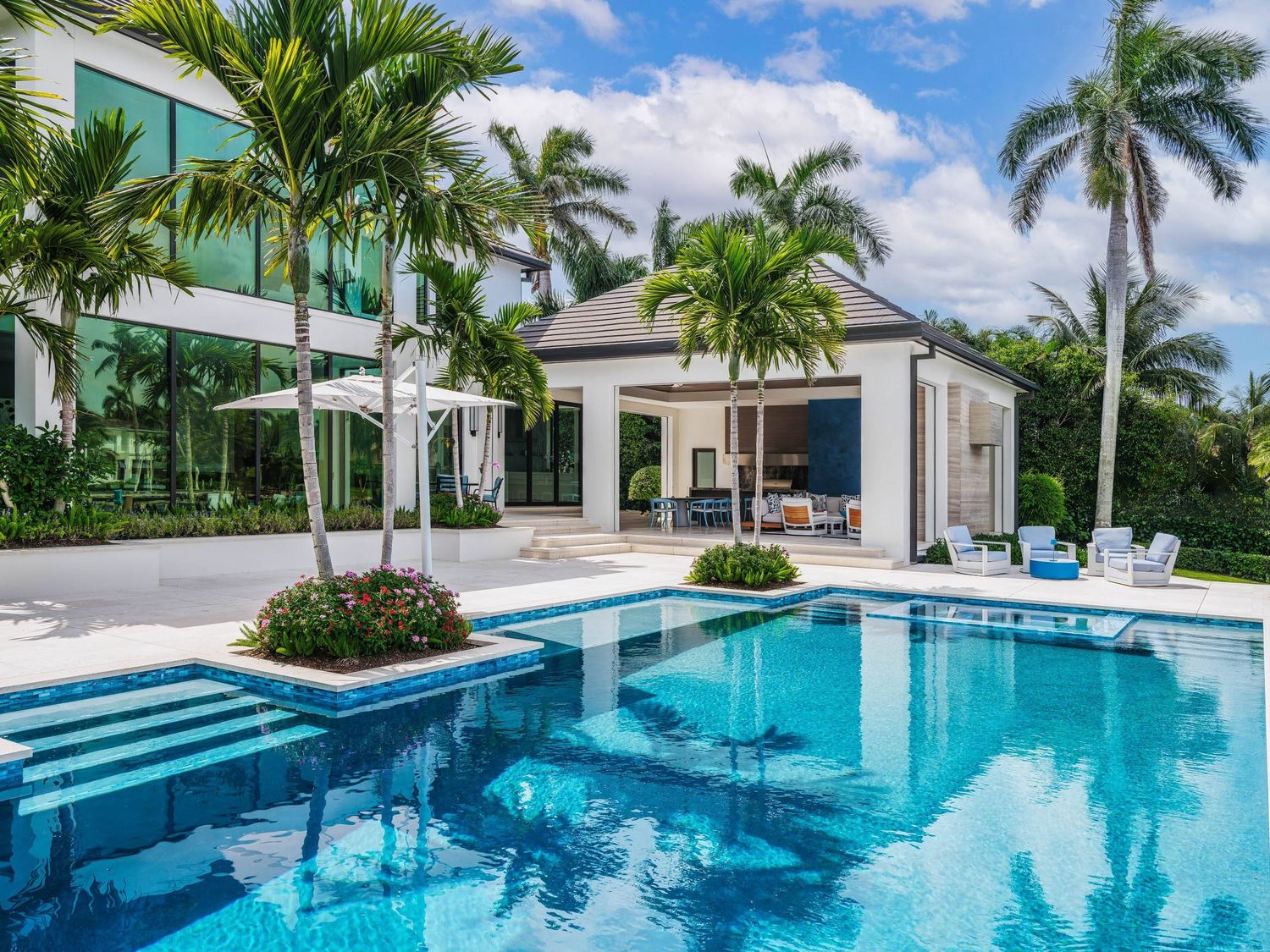 Luxury modern mansion with swimming pool and tropical palm trees.