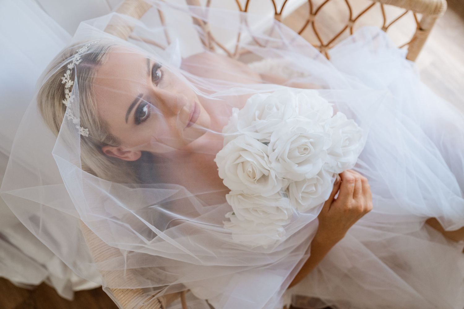 Overhead view of bride in white gown with veil and roses.