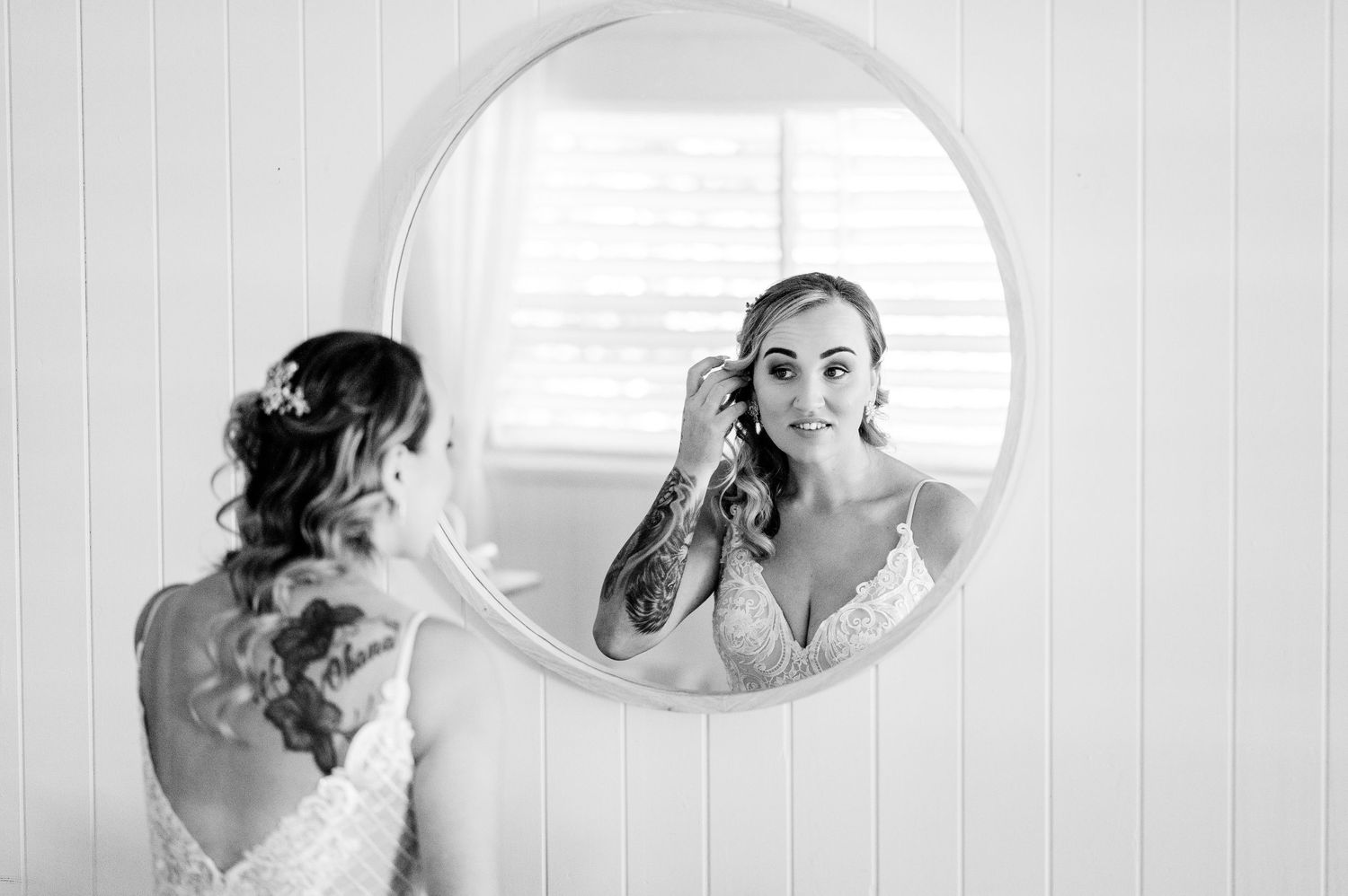 Artistic black and white reflection of bridal preparation in a round mirror.