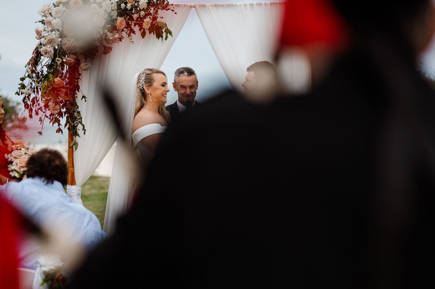 Ceremony scene through floral arch with soft bokeh effect.