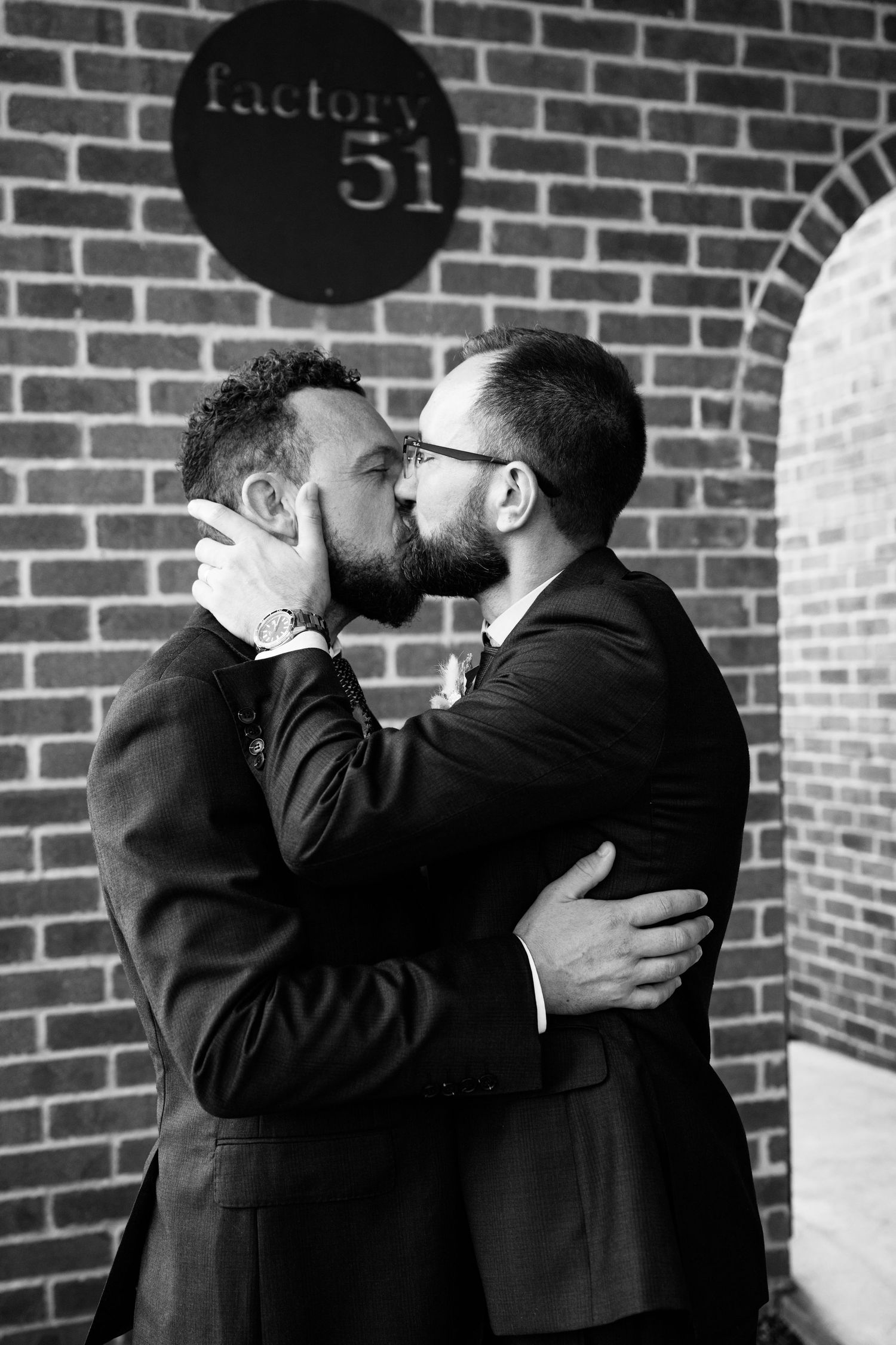 Black and white photo of a romantic kiss outside Factory 51.