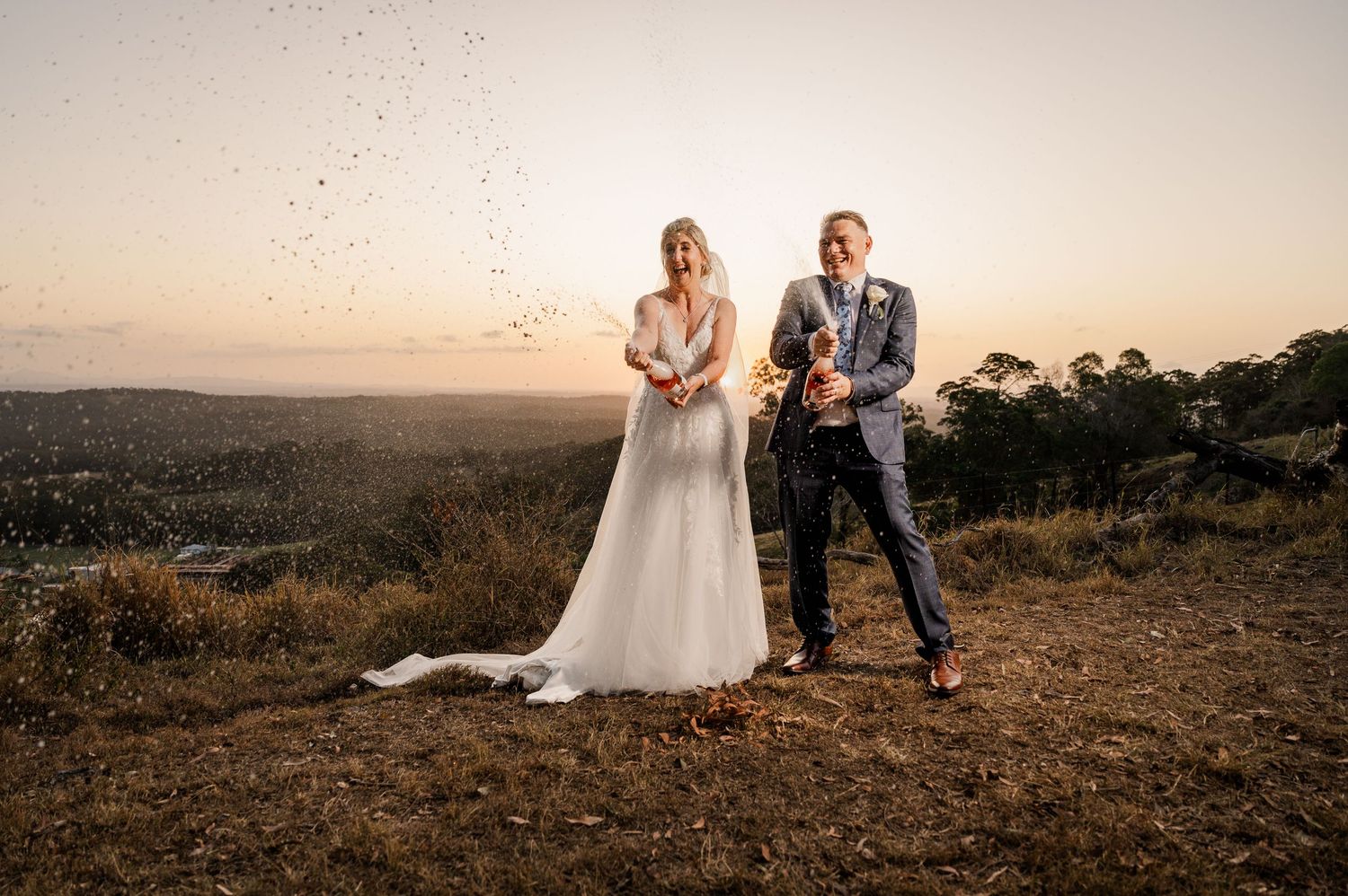 Wedding couple posing on hilltop during golden sunset in countryside.