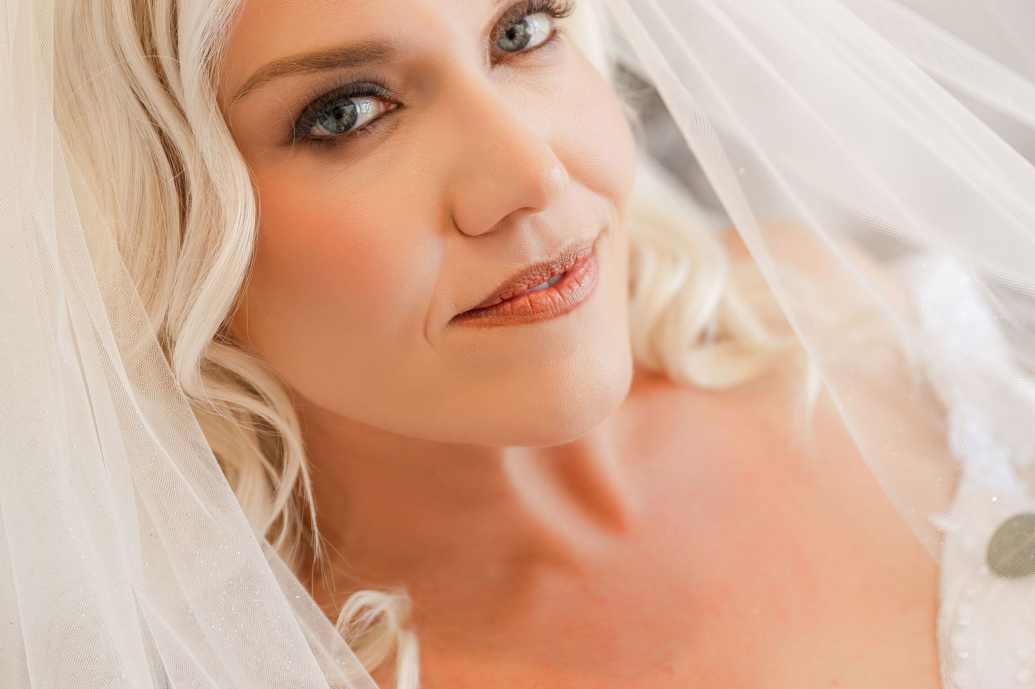 Ethereal bridal portrait with delicate veil and soft lighting.