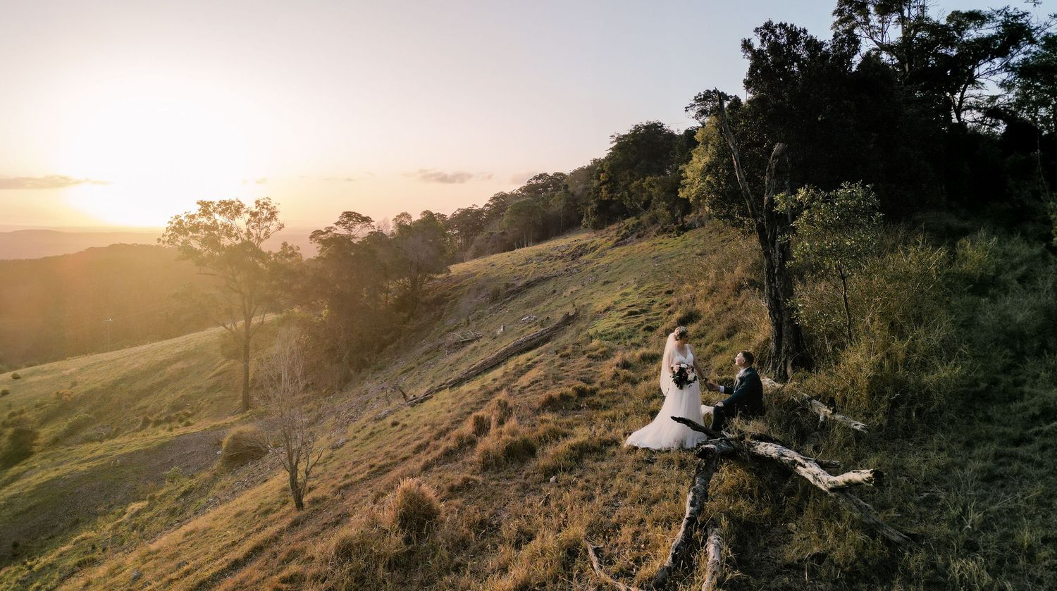 Sunset wedding photo shoot on a grassy hillside overlooking a scenic valley.