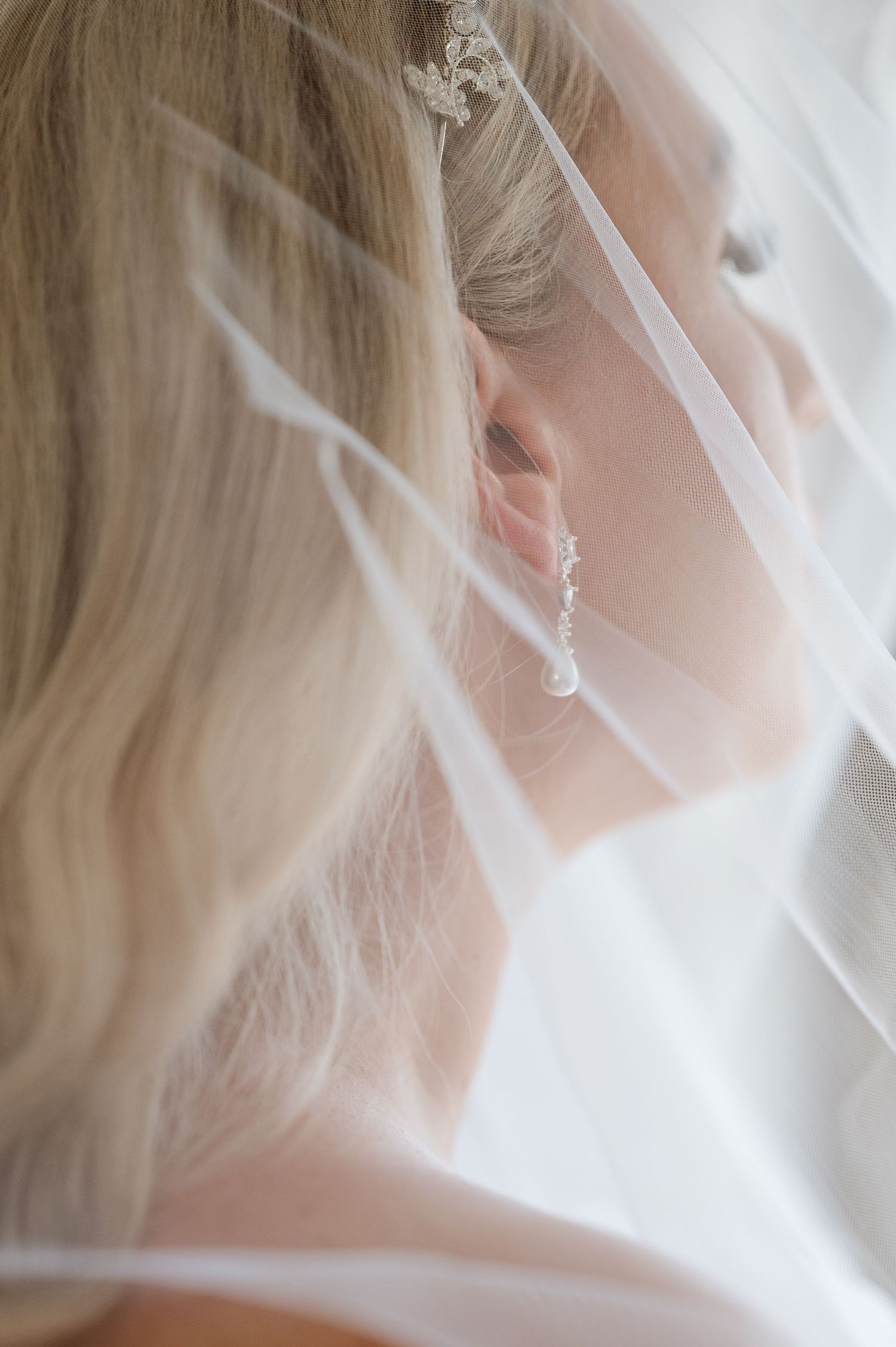 Close-up detail shot of an elegant bridal veil and sparkling earring.