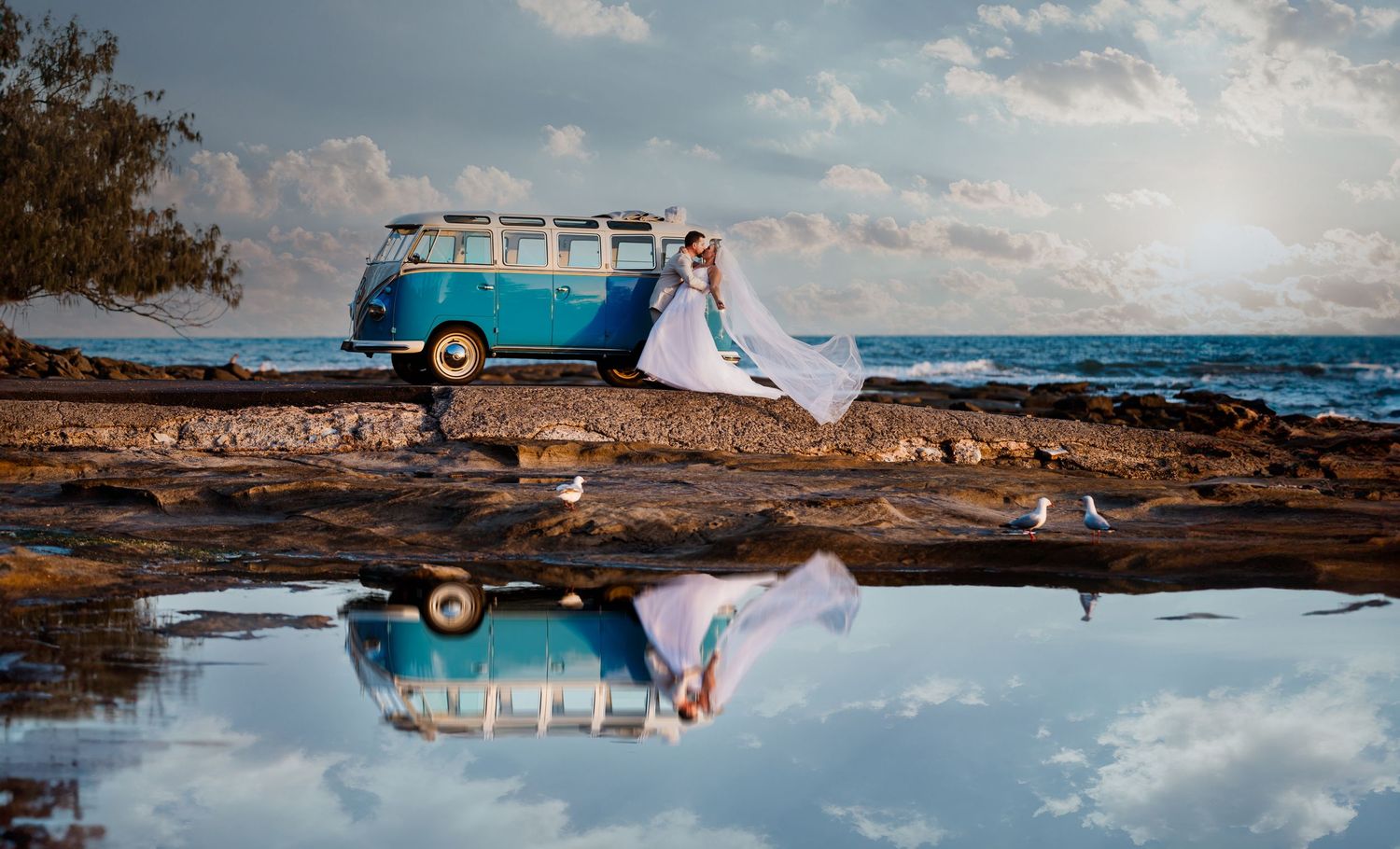 Vintage blue VW bus and wedding scene reflected in coastal tidal pool.